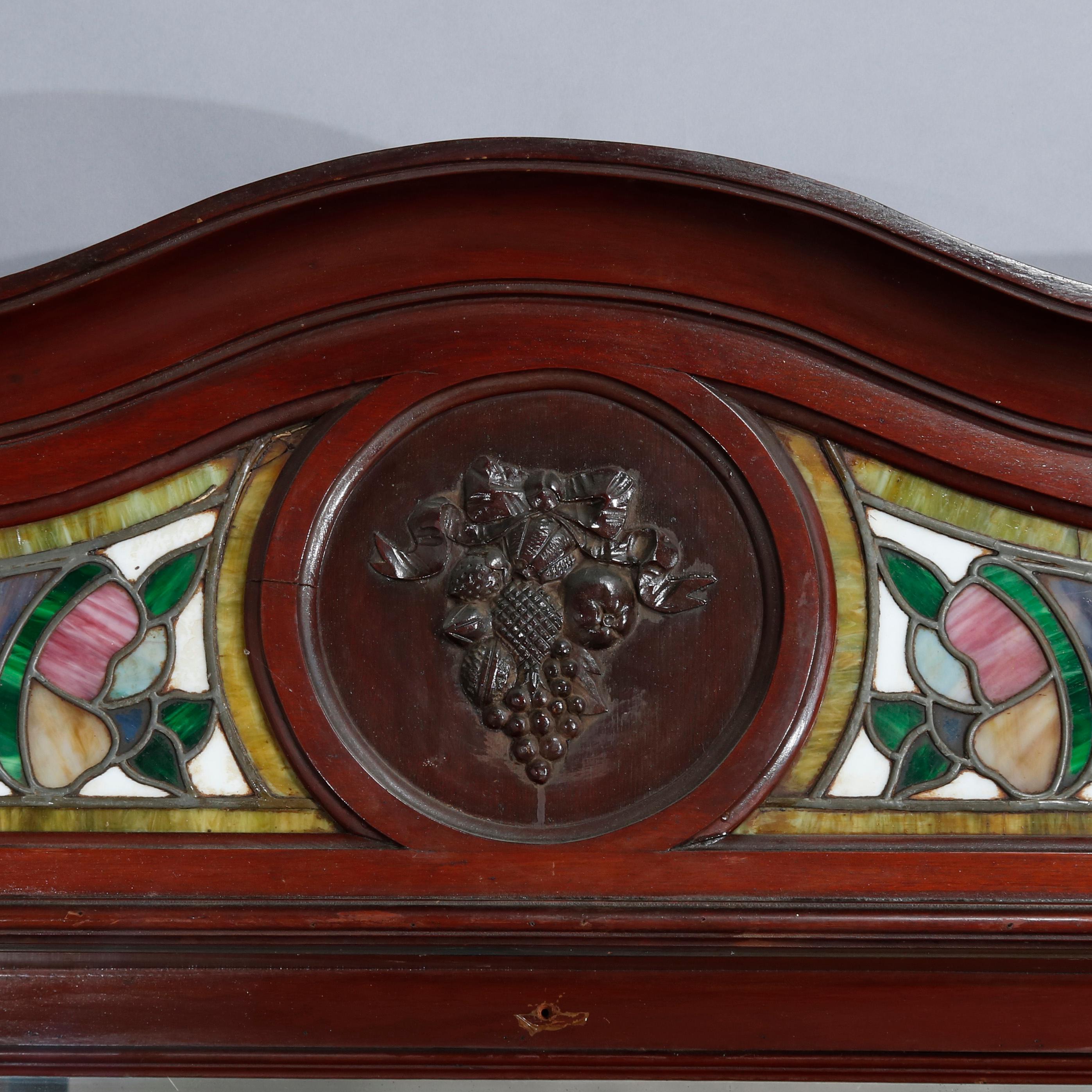 Antique Arts & Crafts bar back offers mahogany construction with shaped crown having central carved fruit and nut medallion flanked by leaded stained and slag glass panels with cornucopia surmounting mirrored back, circa 1910

Measures: 73