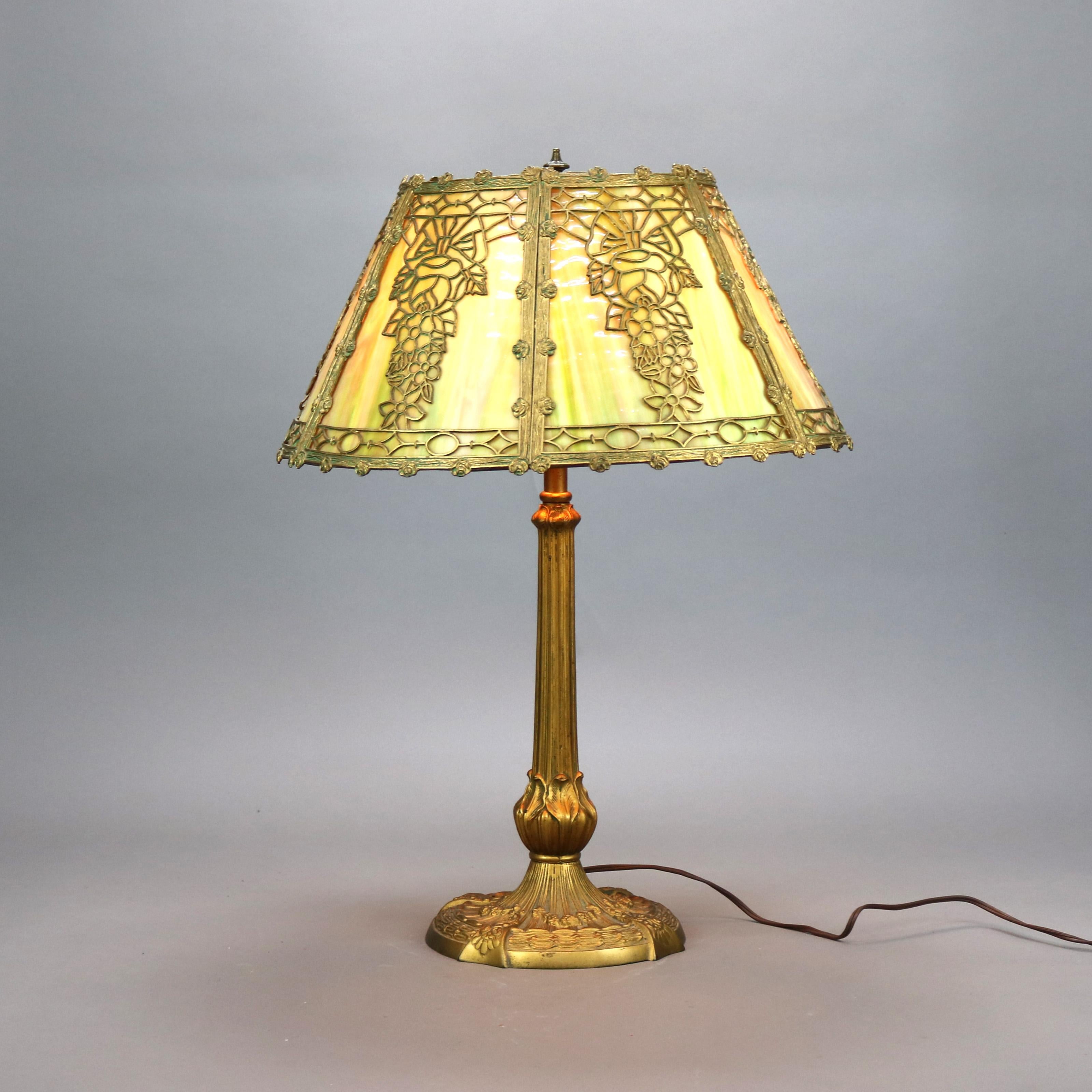 An antique Arts and Crafts table lamp by Miller Lamp Co. offers floral filigree cast shade housing slag glass panels over cast triple socket base, maker mark on base as photographed, c1920

Measures - 25''H x 18.5''W x 18.5''D.