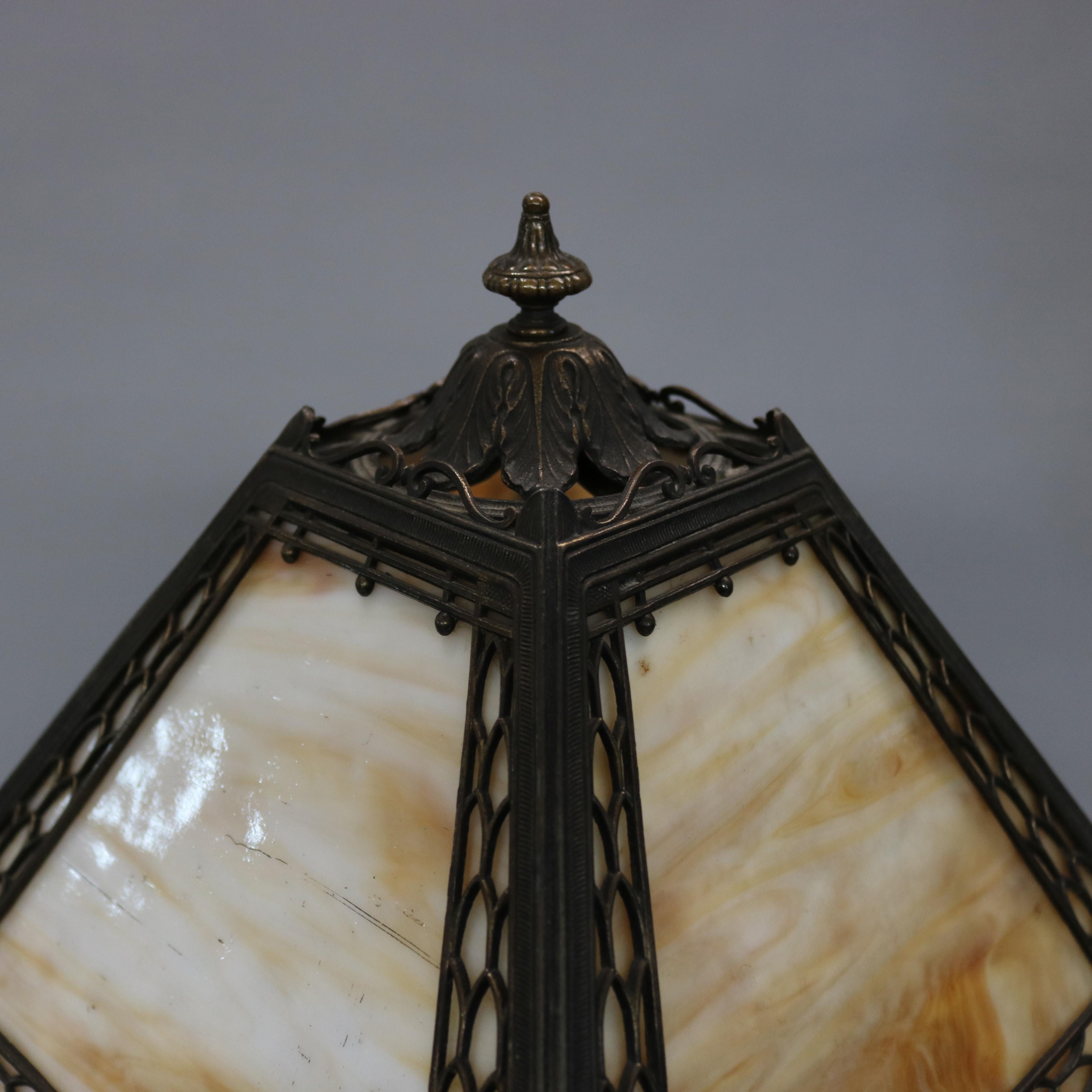 An antique Arts & Crafts table lamp by Miller offers cast filigree shade housing four panels of slag glass and surmounting single socket base, embossed maker as photographed, circa 1920.

Measures: 18.75