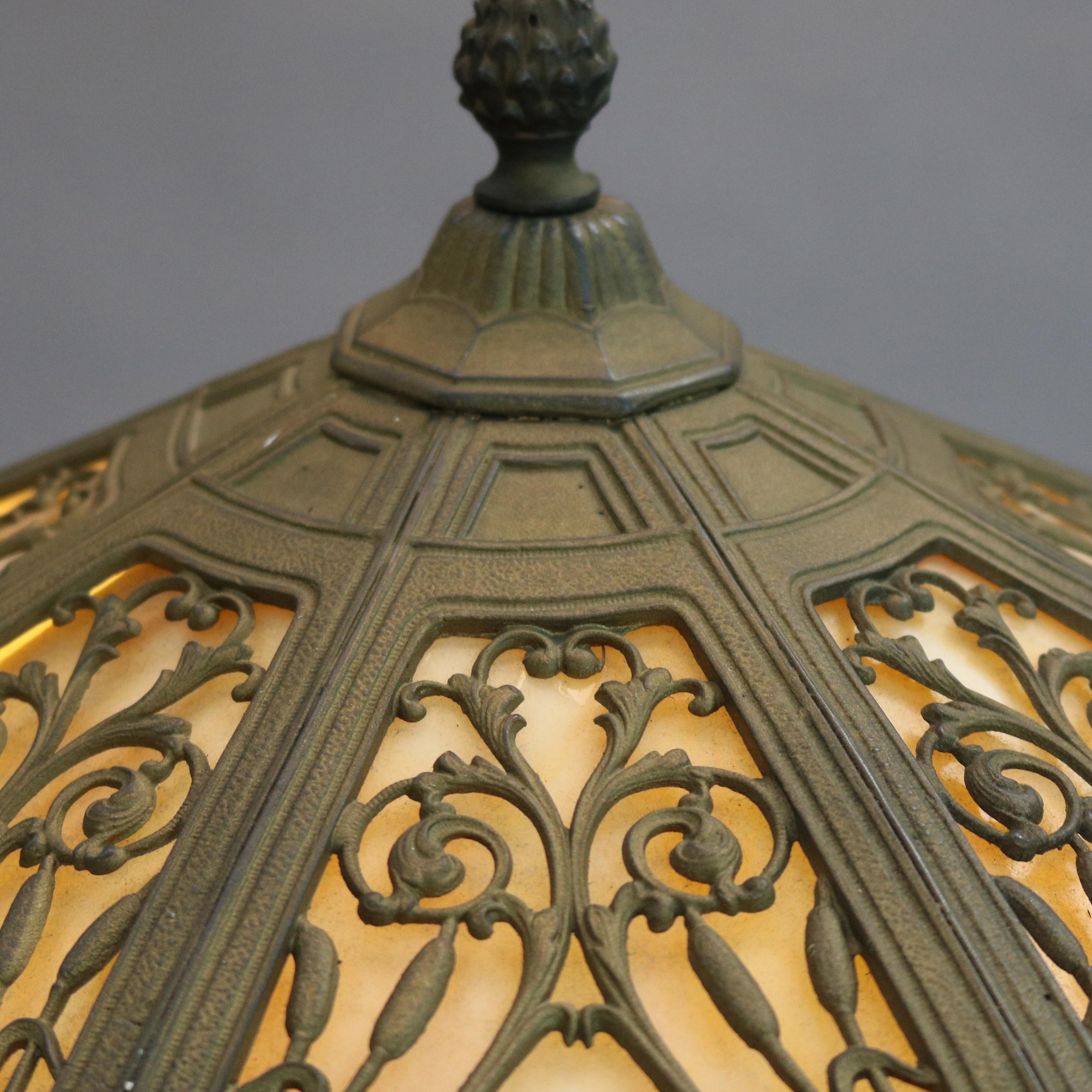 Antique Arts & Crafts table lamp in the manner of Miller Lamp Co. offers foliate and branch filigree cast shade housing bent slag glass panels and surmounting cast double socket base, c1920

Measures: 23