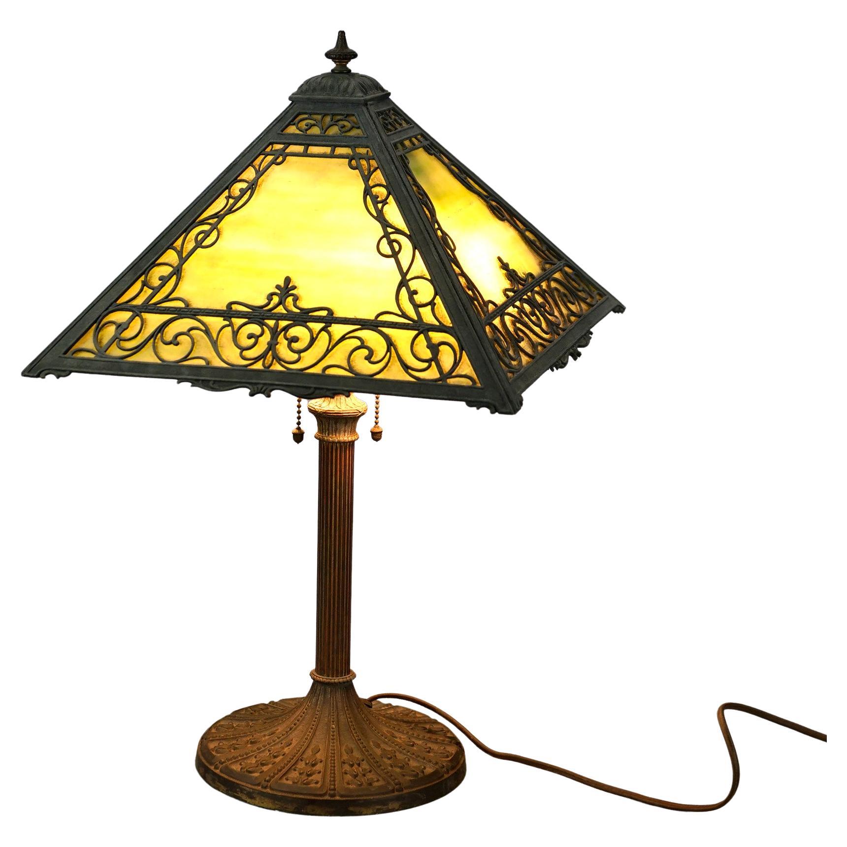 An antique Arts and Crafts table lamp attributed to Miller offers scroll filigree shade housing slag glass over double socket cast base, c1920.

Measures- 20.5''H x 13''W x 13''D.