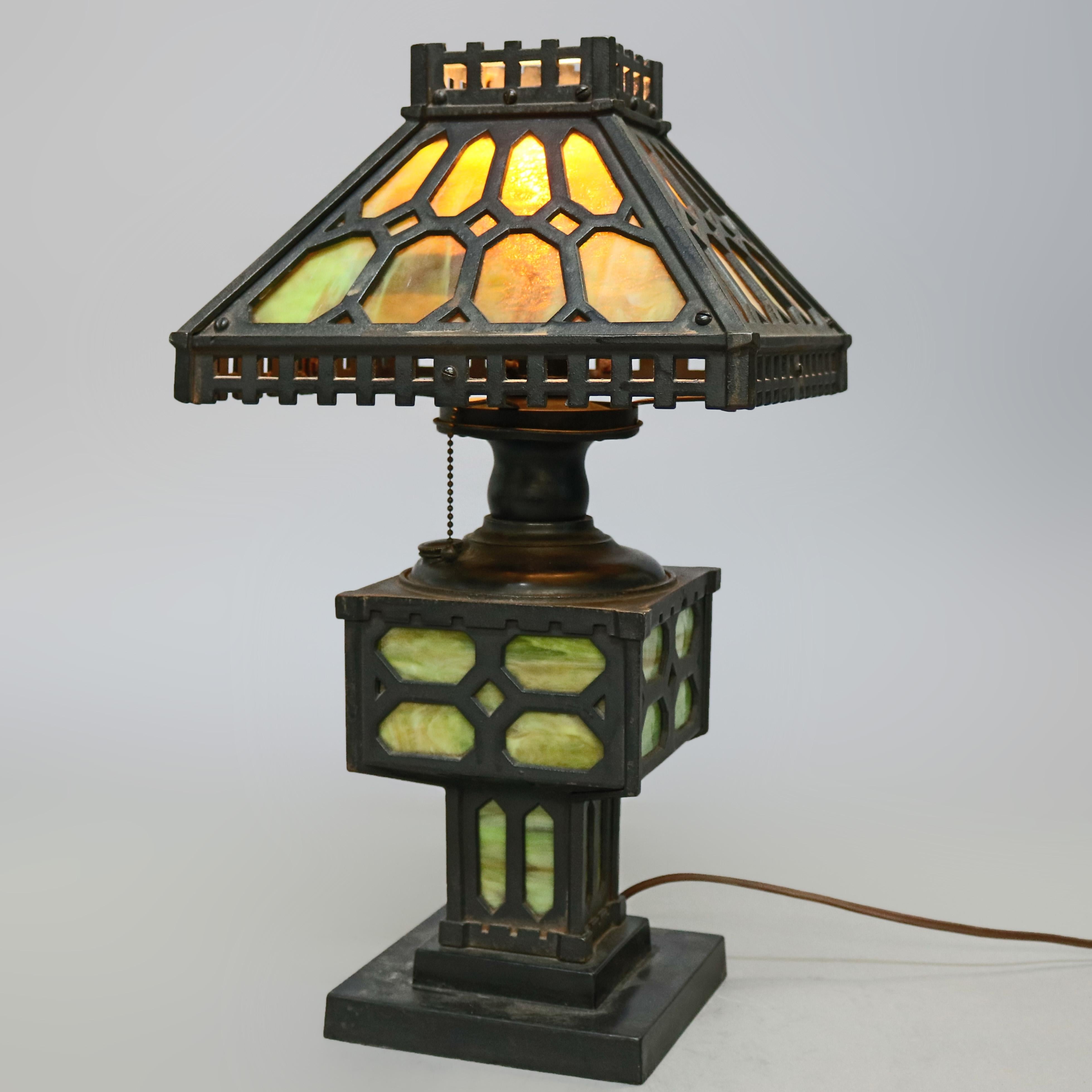 An antique Arts & Crafts Mission table lamp offers ebonized cast iron frame with slag glass panels throughout, single socket and electrified, attributed to Bradley & Hubbard, circa 1920

Measures- 20