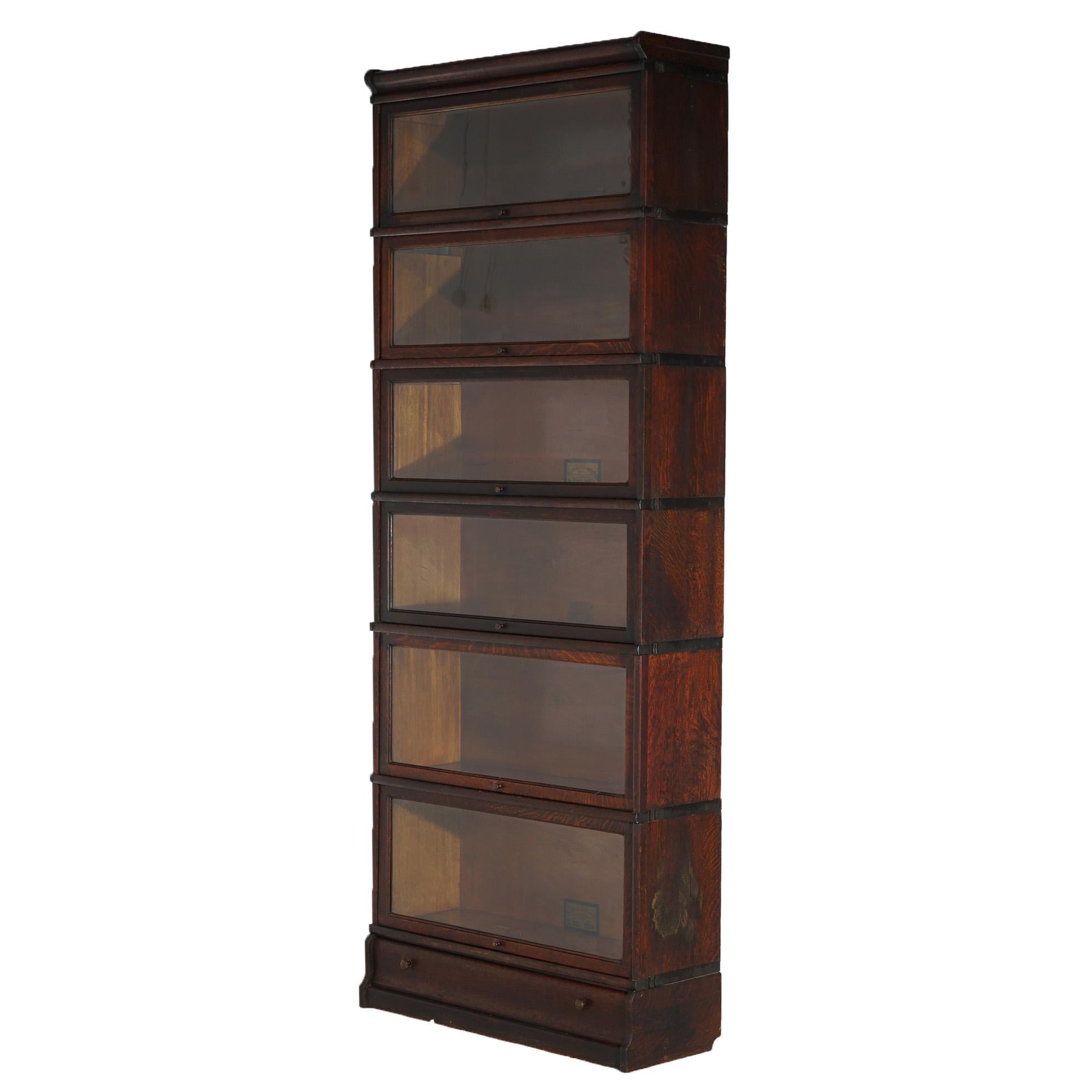 An antique Arts and Crafts Mission barrister bookcase by Globe Wernicke offers oak construction with six stacks, each having pull-out glass doors and raised on an ogee base having a single long drawer; maker labels as photographed; c1910

Measures -