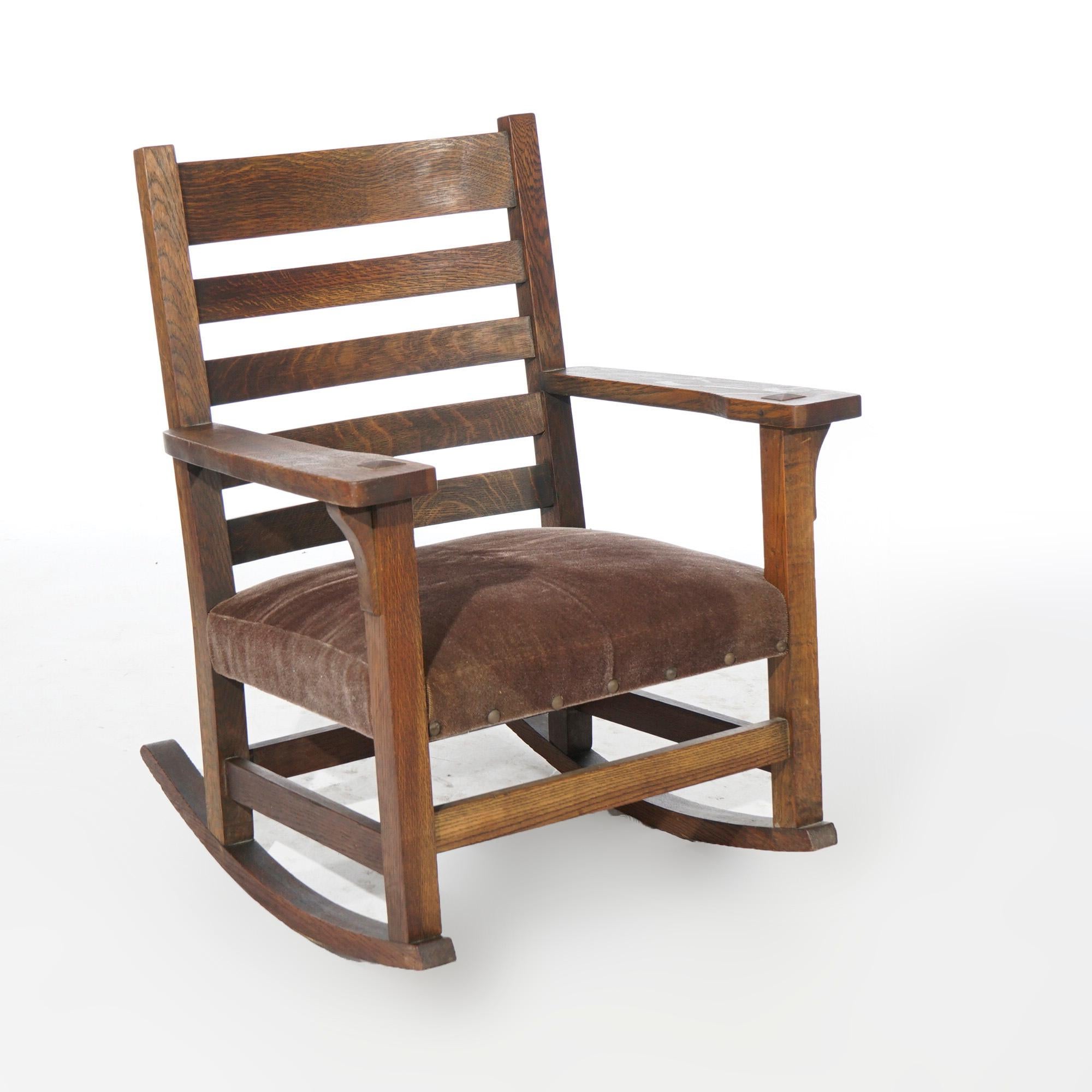 An antique Arts and Crafts Mission rocking chair by JM Young offers quarter sawn oak construction with ladder back over upholstered seat and arms with convex corbels, c1910

Measures- 35''H x 27.5''W x 28.5''D; 16'' seat height

*Ask about