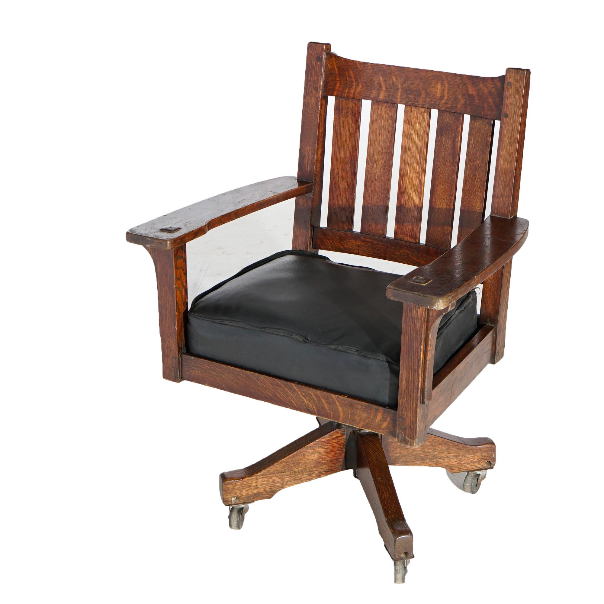 An antique Arts & Crafts office desk chair by L & JG Stickley Handcraft (Cat #850) offers quarter sawn oak construction with slat back over upholstered swivel seat, unsigned, c1910

Measures- 38.5''H x 27.25''W x 23''D.