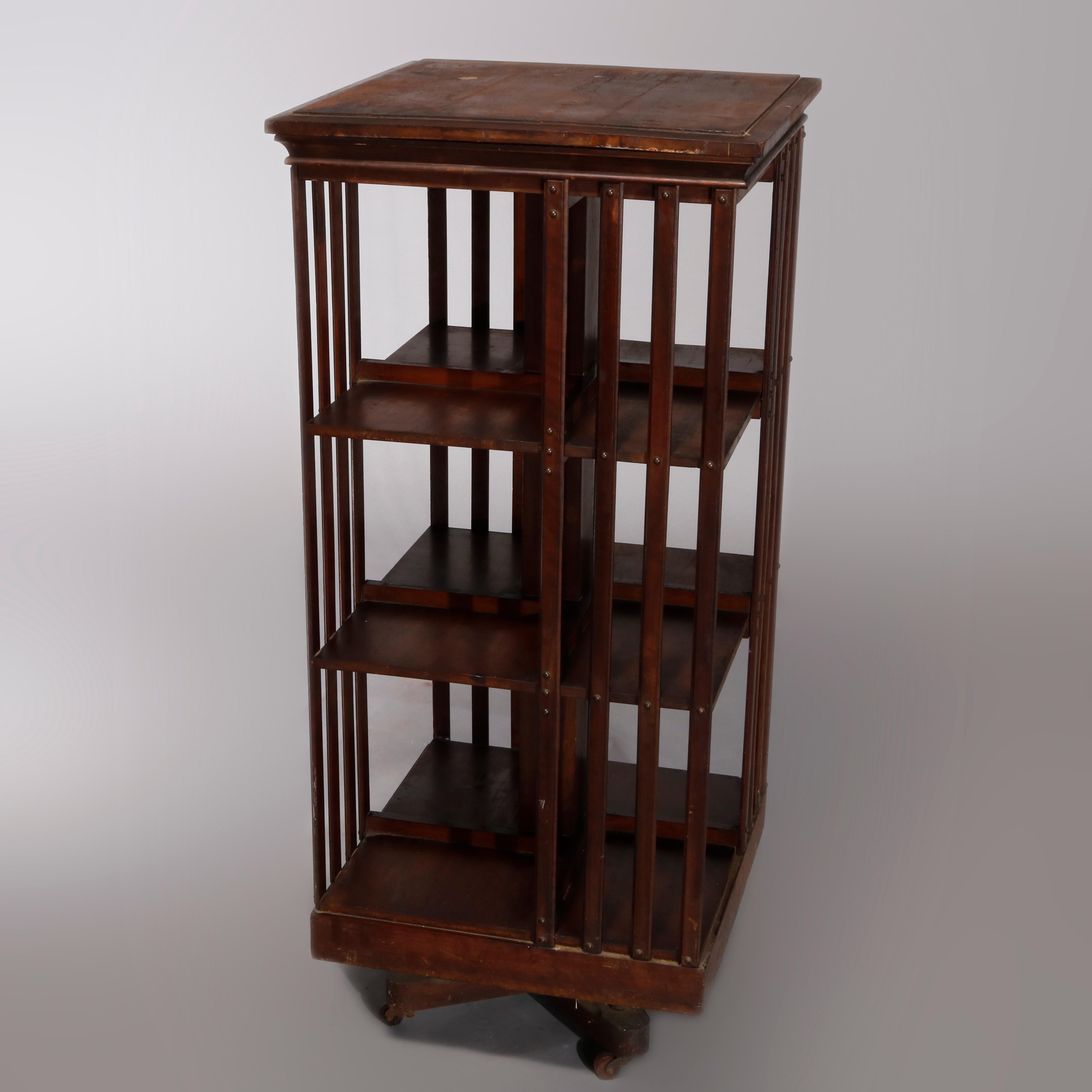 Antique Arts & Crafts Mission oak bookcase by Danner features square form with four shelves and slat sides, bookcase revolves and is seated on quadruped base with wheels, circa 1910.

Measures: 45.5