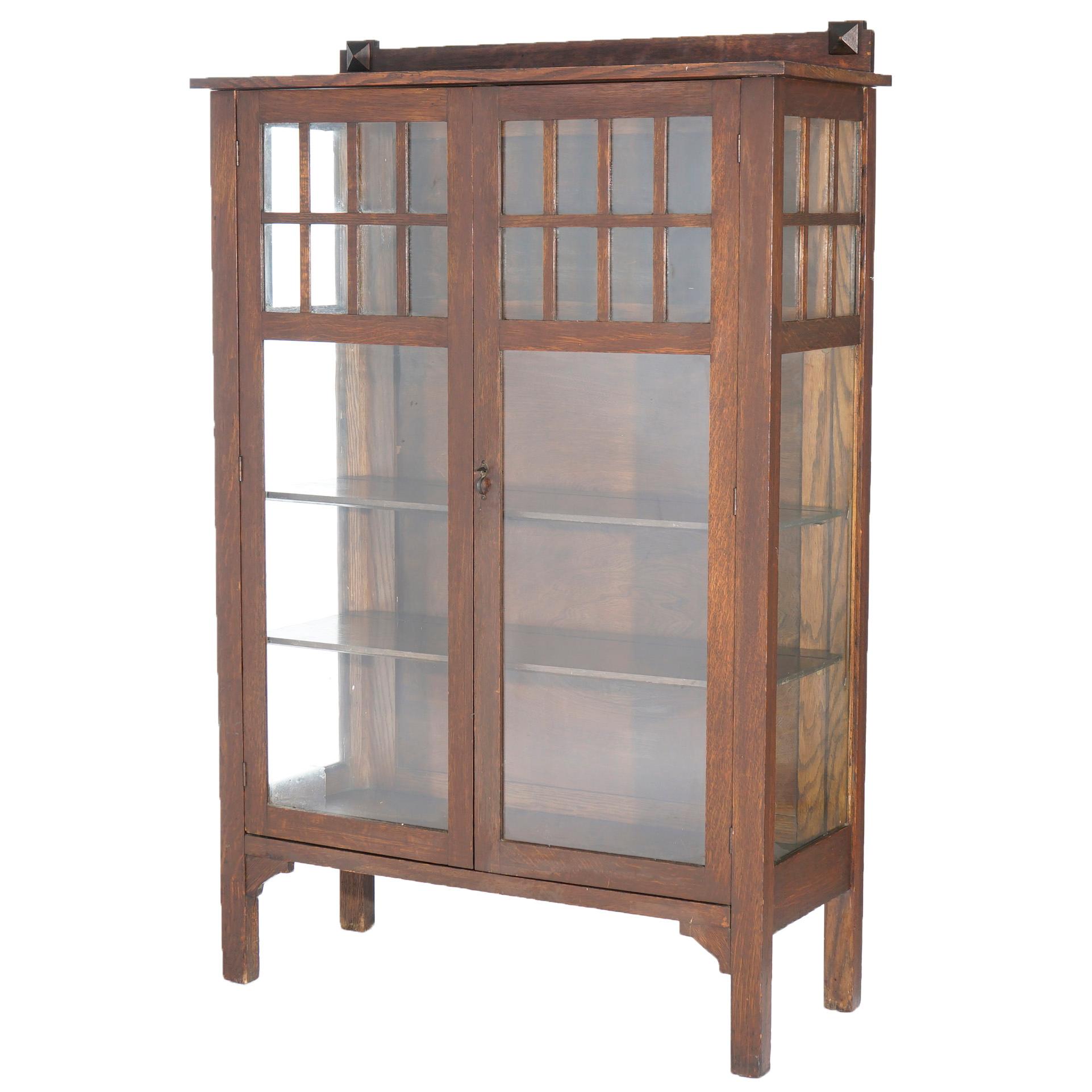 An antique Arts and Crafts Mission china cabinet by Larkin offers quarter sawn construction with upper backsplash surmounting case with glass side and doors opening to shelved interior, raised on square and straight legs with decorative corbels,