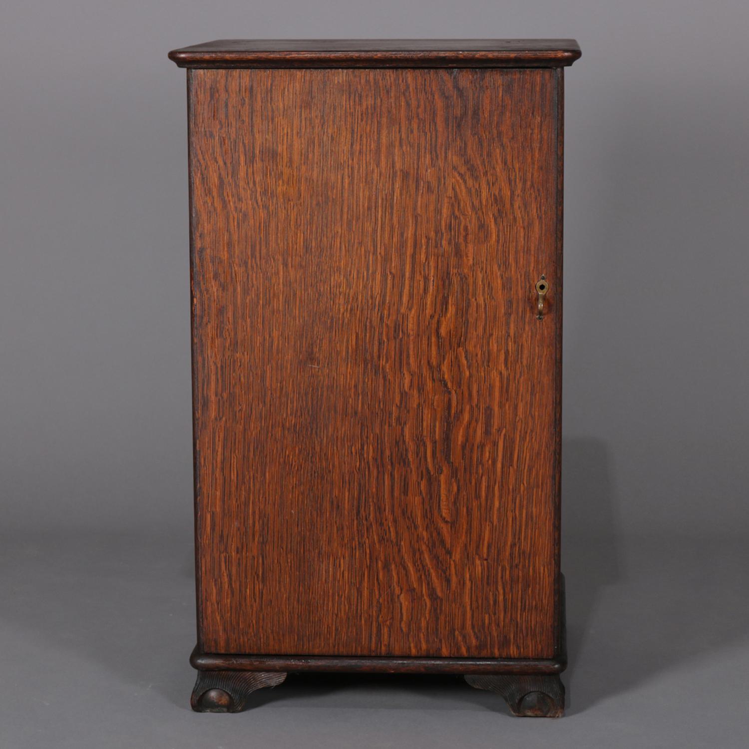 Antique Arts & Crafts mission oak Edison cylinder and phonograph cabinet features single door opening to adjustable shelf interior with two shelves and seated on carved stylized claw and ball feet, circa 1910.

Measures: 35