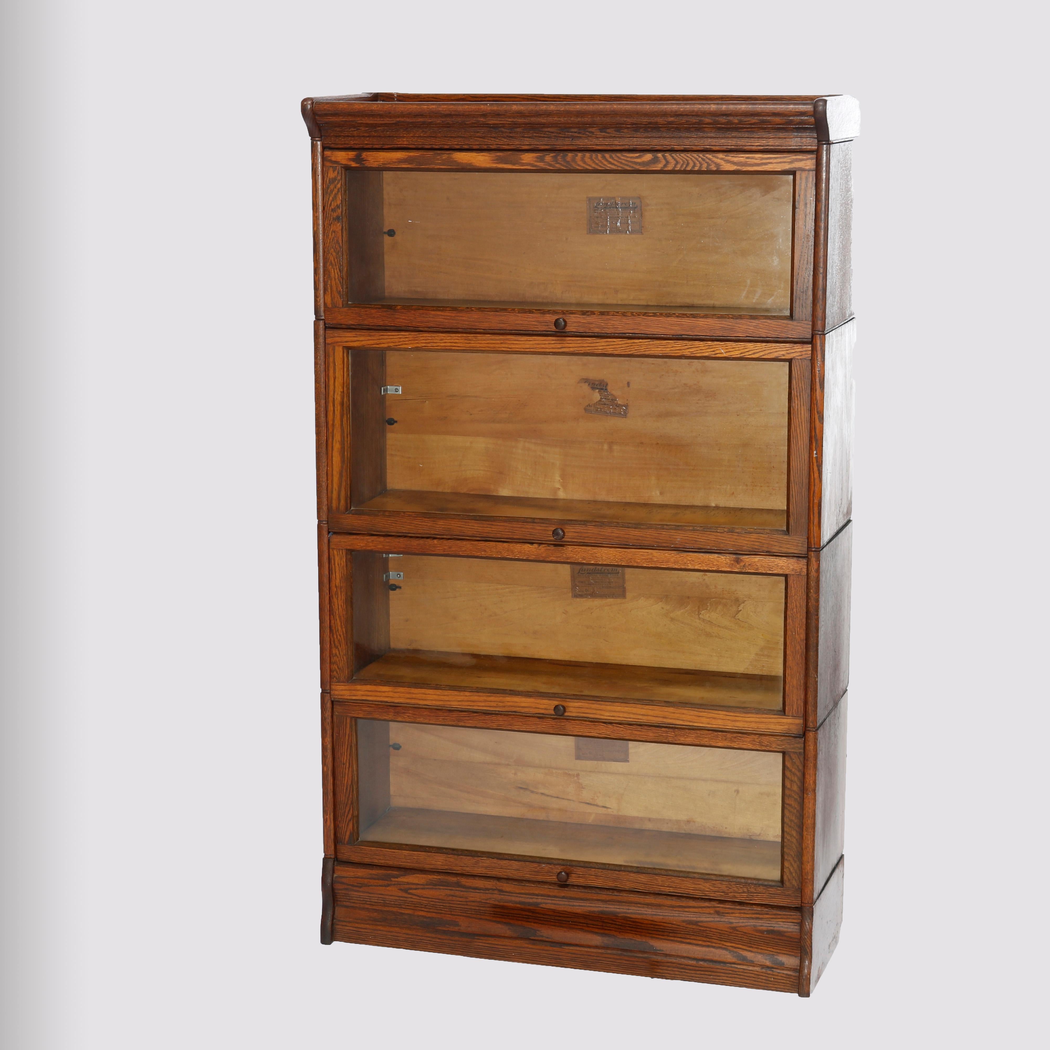 An antique Arts & Crafts Mission barrister bookcase by Lundstrom offers quarter sawn oak construction with four stacks, each having pull-out glass doors, raised on ogee base, and maker labels as photographed, c1910

Measures - 57''h x 33.75''w x