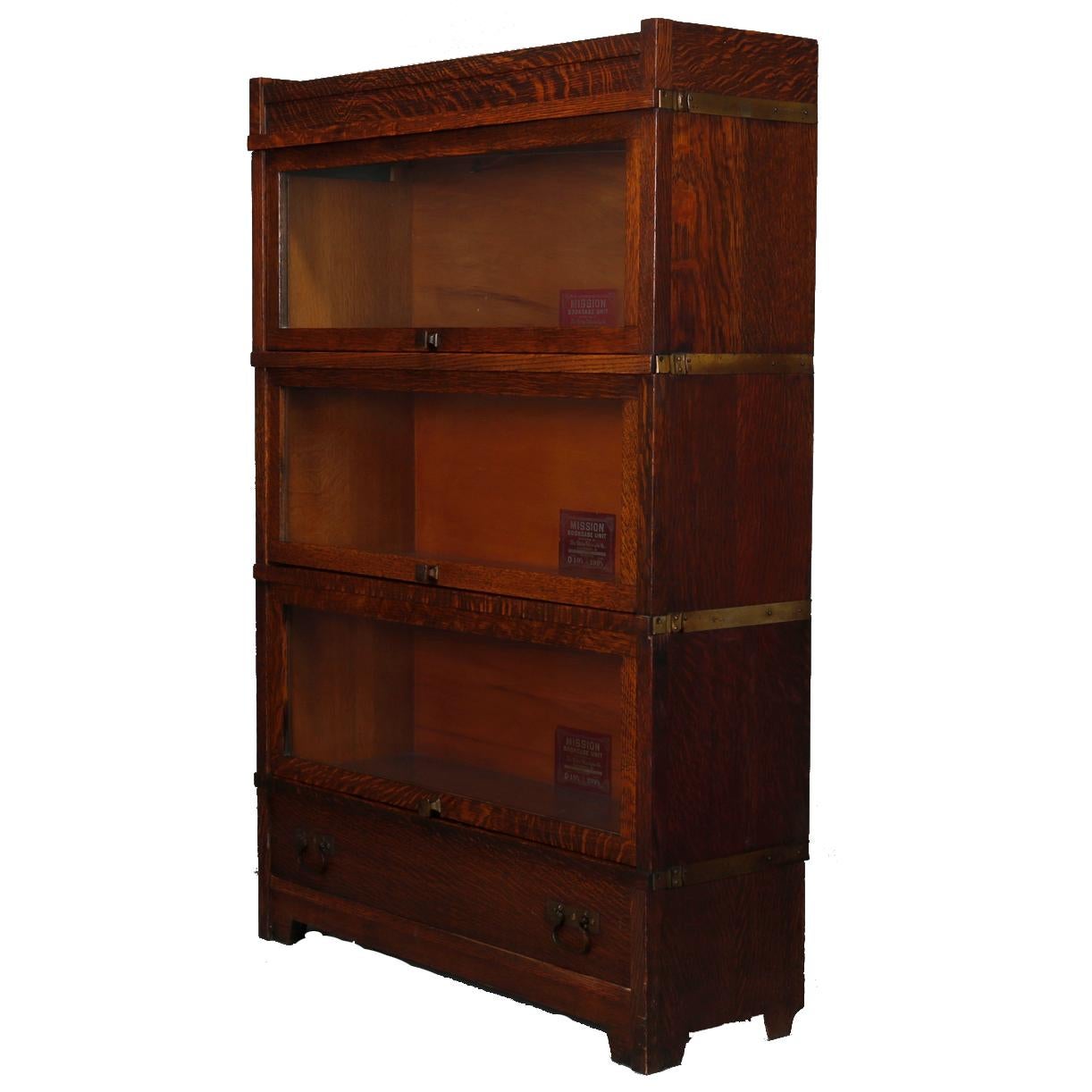 An antique Arts & Crafts Barrister Mission bookcase by Globe Wernicke offers quarter sawn oak construction with three stacks having pull out glass doors with square knobs, raised on straight and square legs, original maker label as photographed,