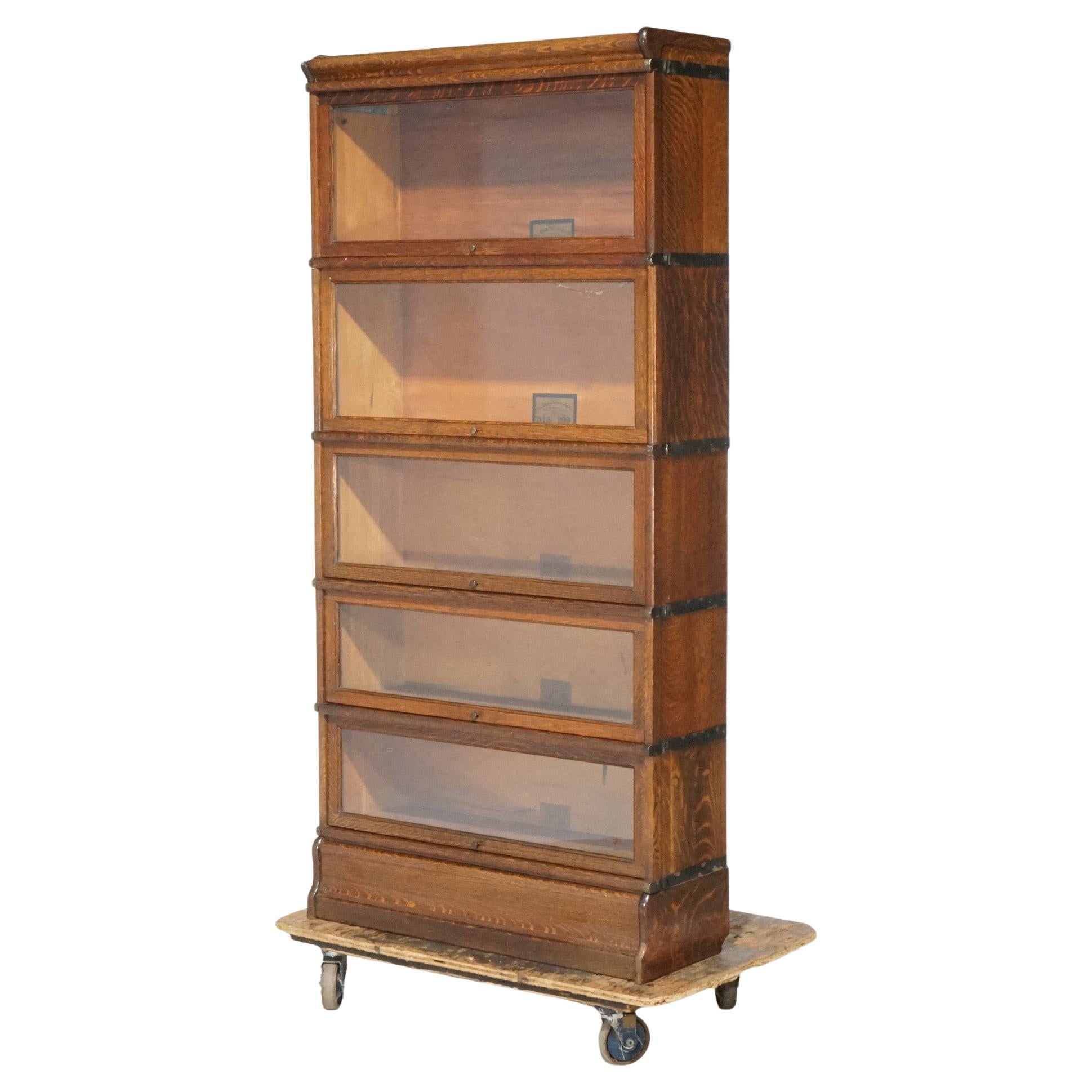 An antique Arts and Crafts Mission barrister bookcase by Globe Wernicke offers quarter sawn oak construction with five stacks, each having pull out glass doors, and raised on ogee base; maker labels as photographed; c1910

Measures - 72