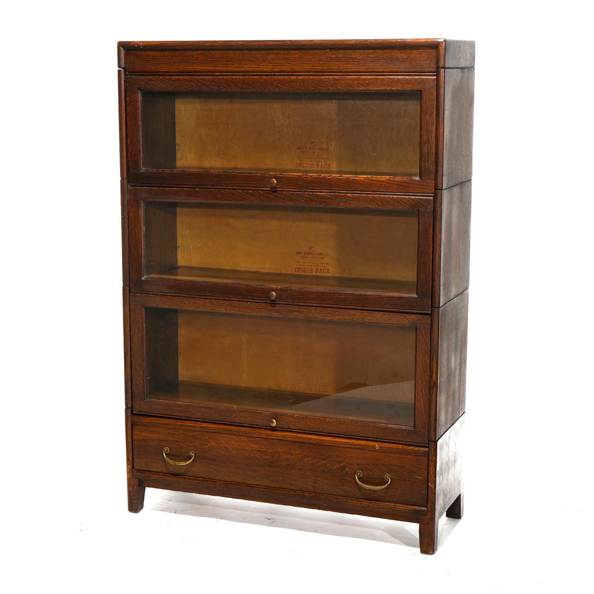 An antique Arts and Crafts Mission barrister bookcase in the manner of Globe Wernicke offers quarter sawn oak construction with three stacks, each having pull out glass shelves and a lower with a single long drawer, raised on square and straight