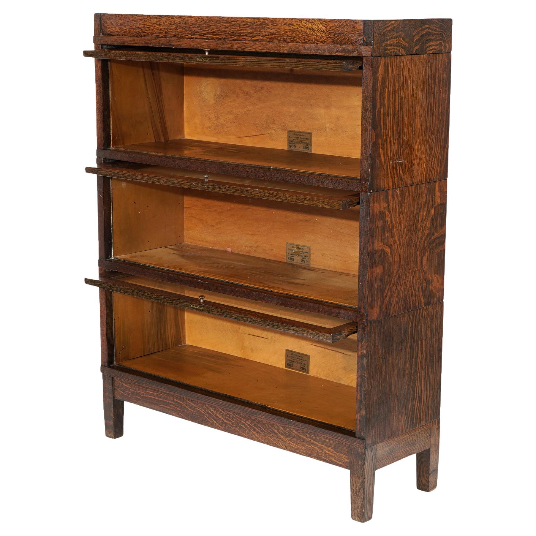 An antique Arts and Crafts Mission barrister bookcase by Globe Wernicke offers quarter sawn oak construction with three stacks each having pull out glass doors and raised on square and straight legs, maker labels as photographed, c1910

Measures-