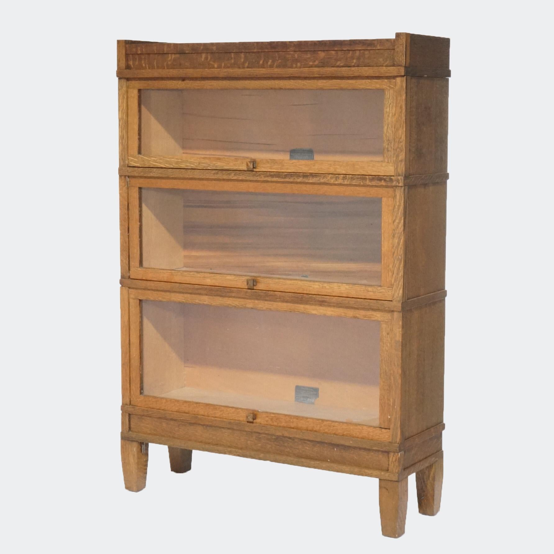 Antique Arts and Crafts barrister bookcase by Globe Wernicke offers oak construction with three stacks, each having a pull out glass door, raised on straight legs, maker label as photographed, c1910

Measures - 50.5