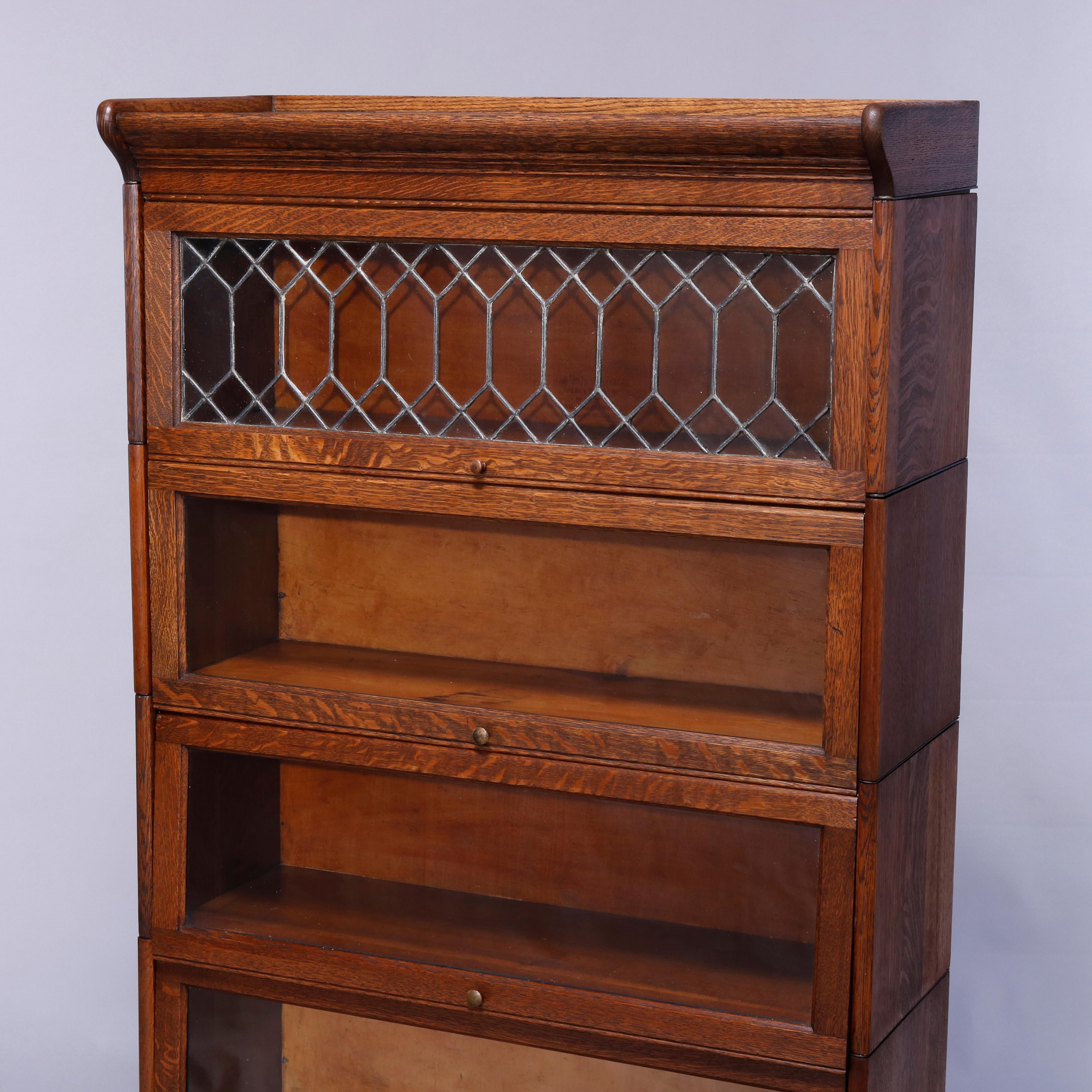 An antique Arts and Crafts Mission barrister bookcase by Gunn offers quarter sawn oak construction with four stacks, one with leaded glass and three having pull out glass doors, raised on ogee base, label remnant as photographed, c1910

Measures: