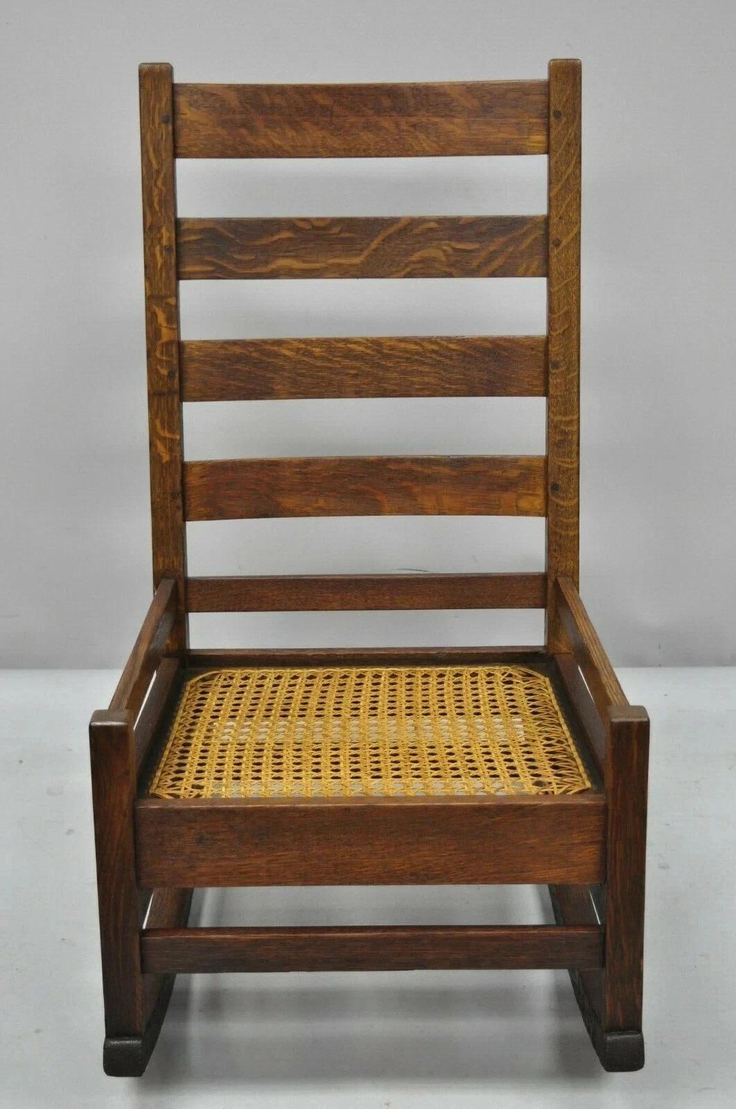 Antique Arts & Crafts Mission Oak Ladder Back Hip Rail Rocker Rocking Chair. Item features a cane seat, ladderback exposed dowel joinery, solid wood construction, beautiful wood grain. Unsigned but possibly by Stickley. Circa Early 20th Century.