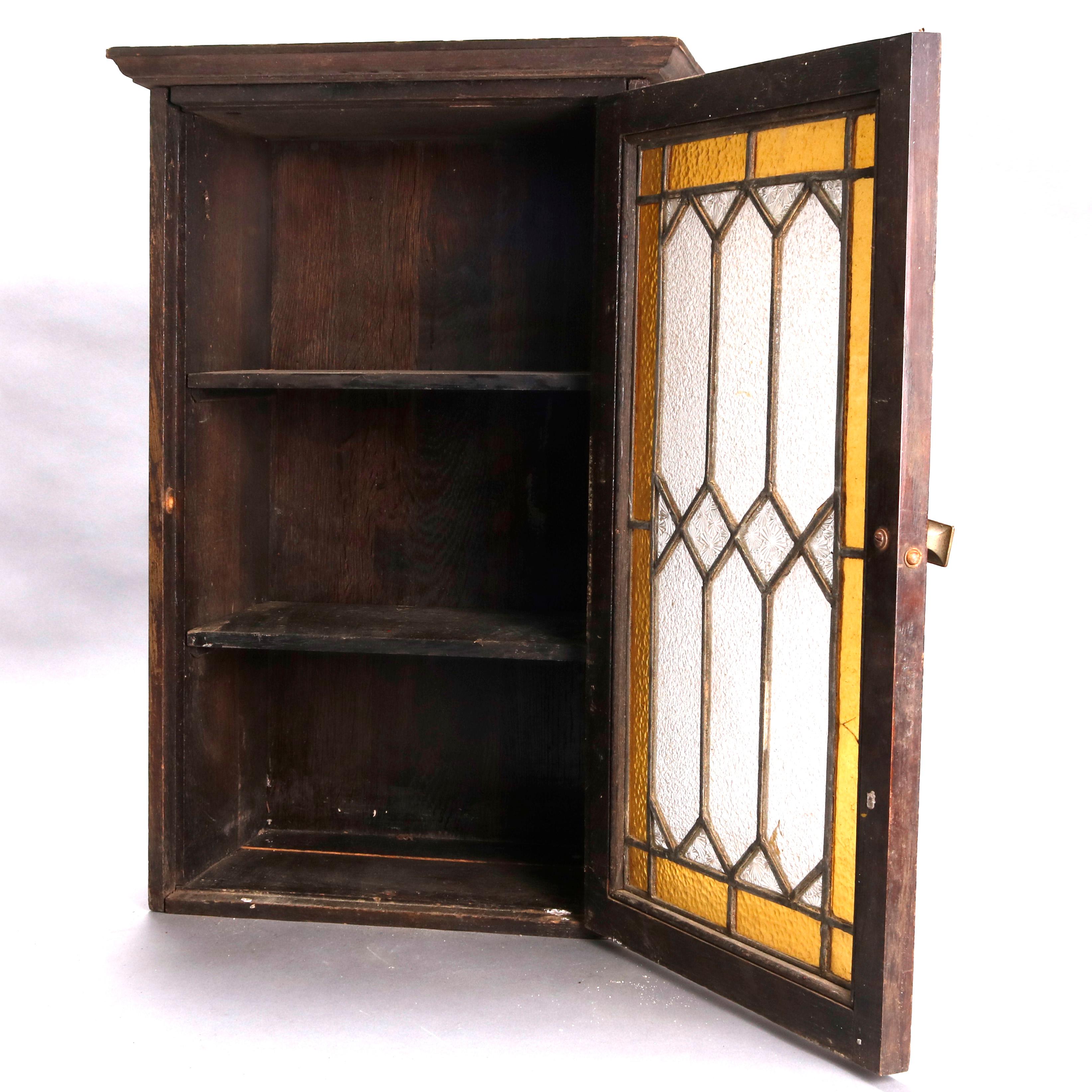 An antique Arts & Crafts mission oak wall cabinet offers single leaded glass door with square cast bronze pull, opening to shelved interior, circa 1910

***DELIVERY NOTICE – Due to COVID-19 we have employed LIMITED-TO-NO-CONTACT PRACTICES in the