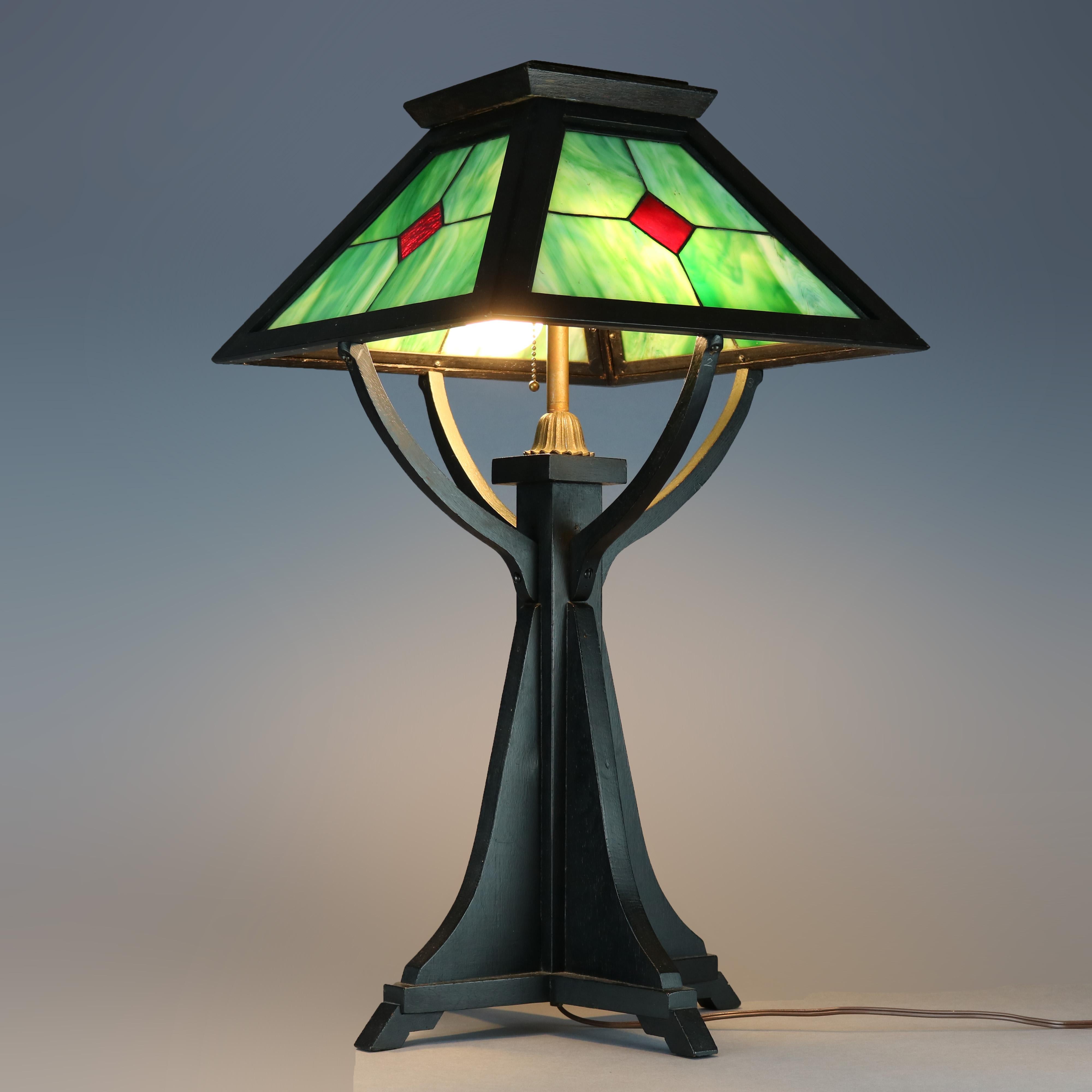 An antique and large Arts & Crafts Prairie School table lamp offers leaded slag glass shade with pyramidal oak cap surmounting flared base with double sockets, circa 1910.

Measures: 27.25