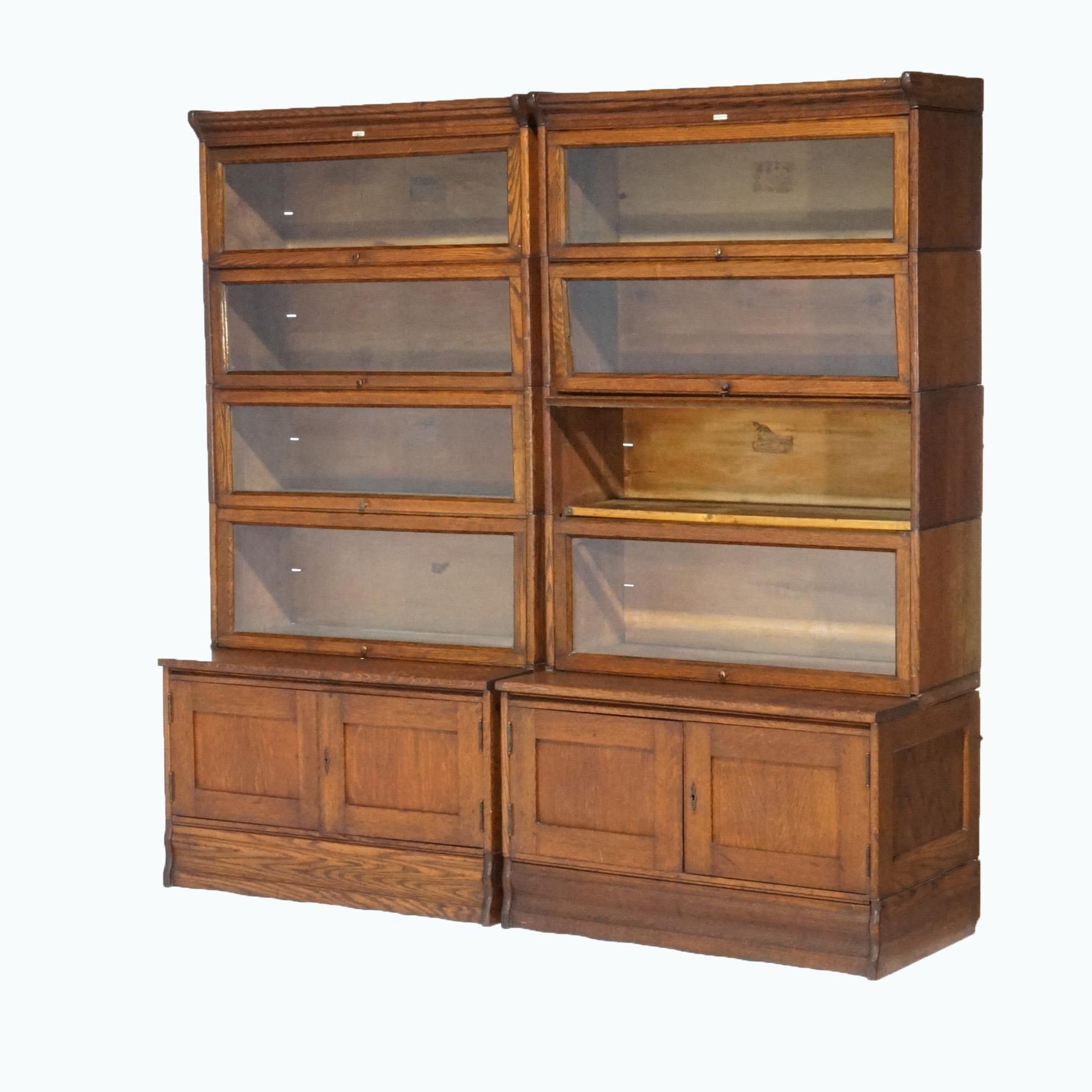 An antique pair of Arts and Crafts Mission bookcases by Lundstrom offer oak construction with four stacks, each having pullout glass doors, seated on double door cabinets, maker label as photographed, c1910

Measures- 67.75''H x 33.5''W x 19.5''D;