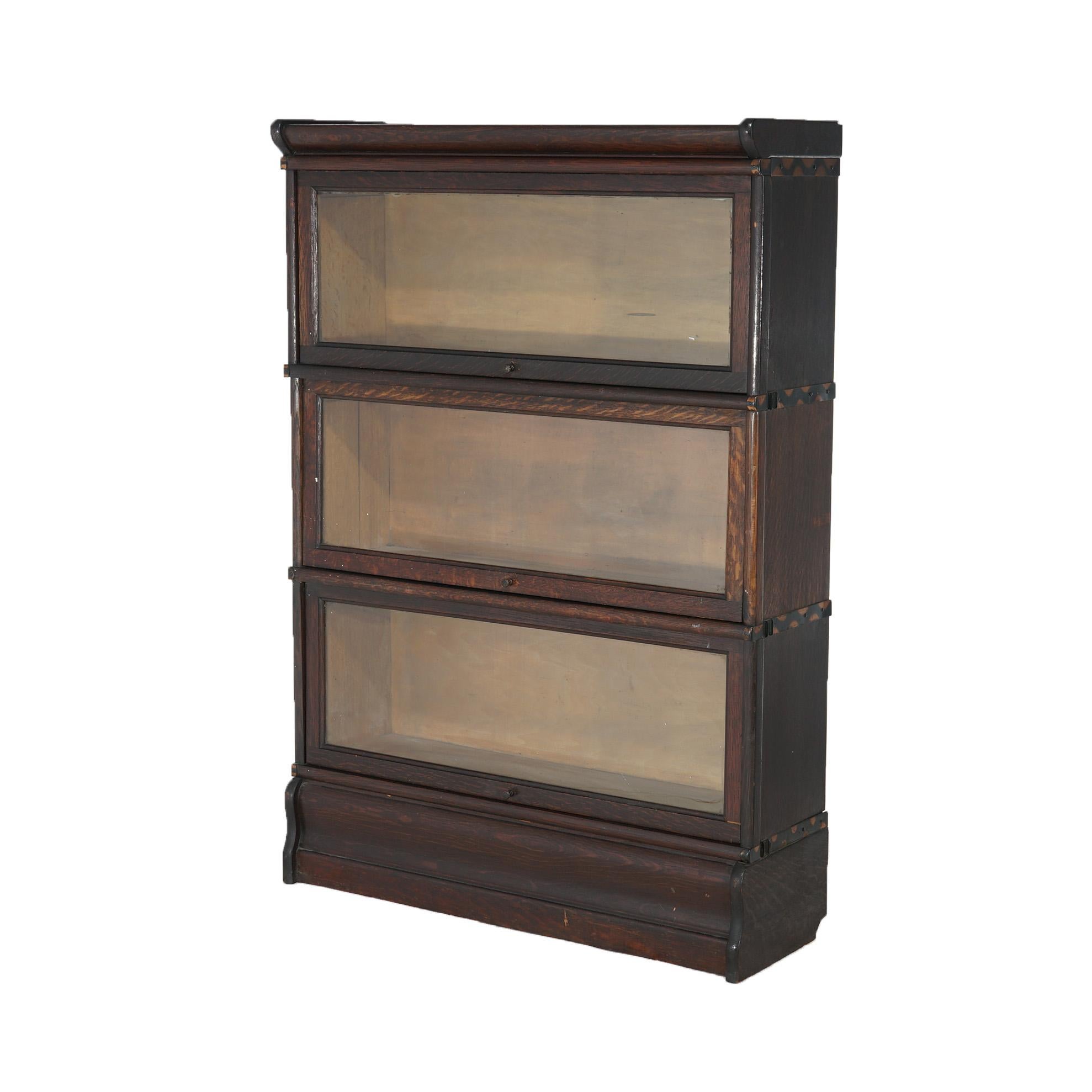 An antique Arts and Crafts Mission barrister bookcase by Macey offers oak construction with three stacks, each having pullout glass doors; raised on ogee base, maker label as photographed, c1910

Measures - overall 45.25