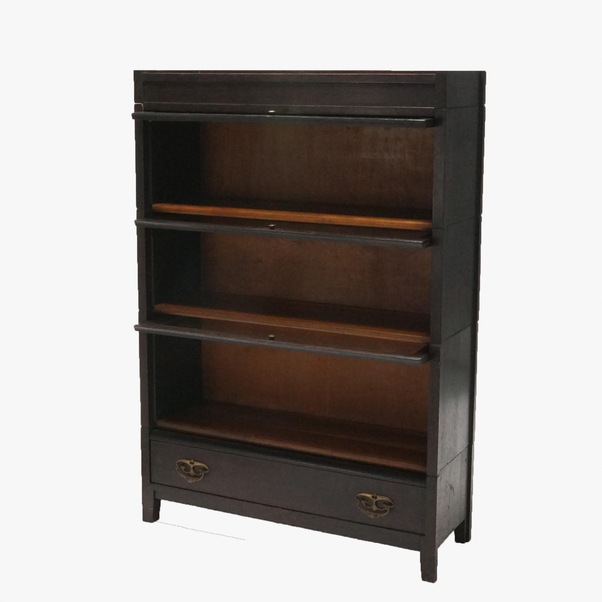 An antique Arts & Crafts Mission barrister bookcase offers oak construction with three stacks, the top with leaded glass door, and lower drawer, en verso Grand Rapids label as photographed, c1910

Measures- 50.5''H x 34.75''W x 12.25''D.