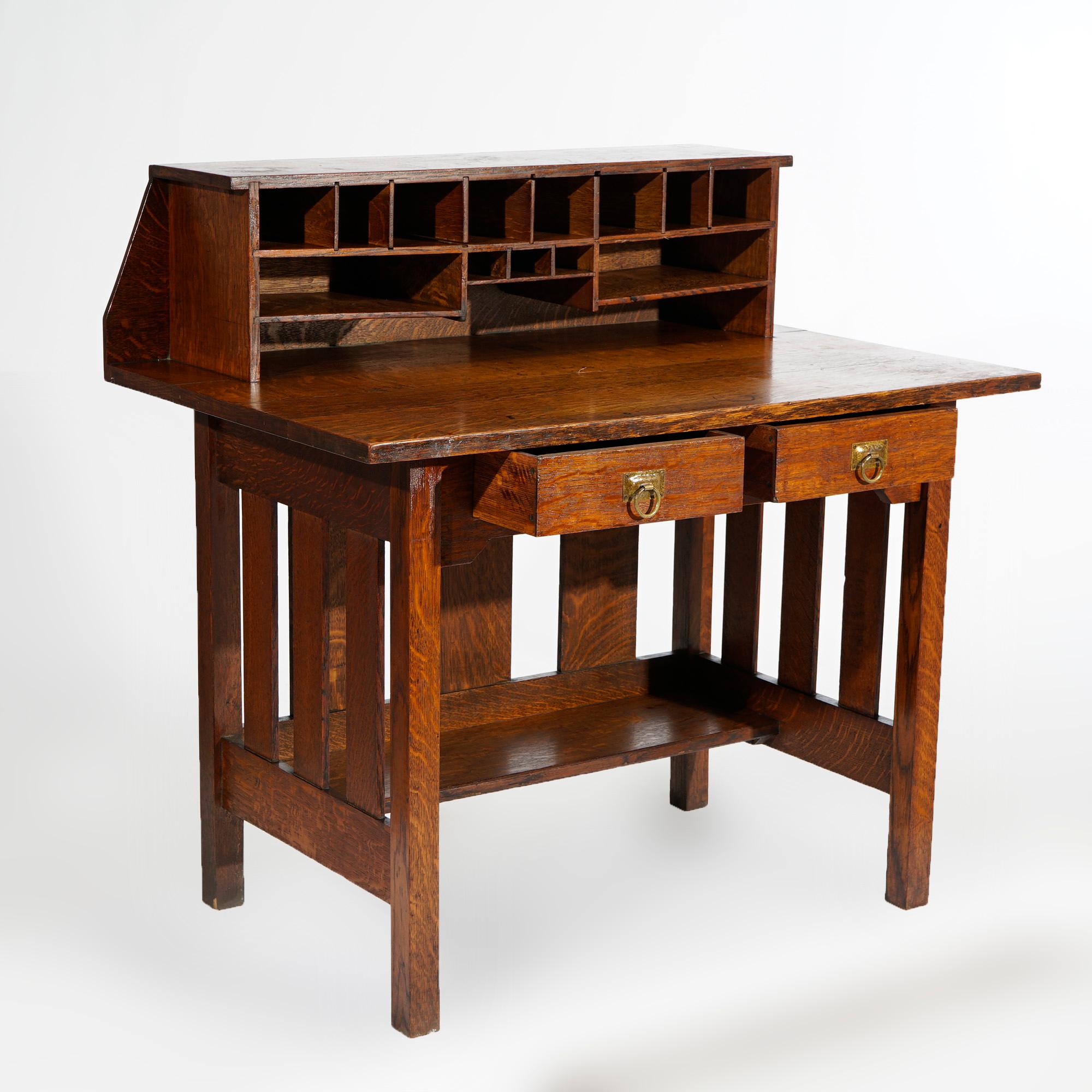An antique Arts and Crafts Mission operator desk by Stickley Brothers offers quarter sawn oak construction with upper having pigeon holes over desk with two drawers and slat sides, unsigned, reminiscent of a railroad desk, circa 1910

Measures-