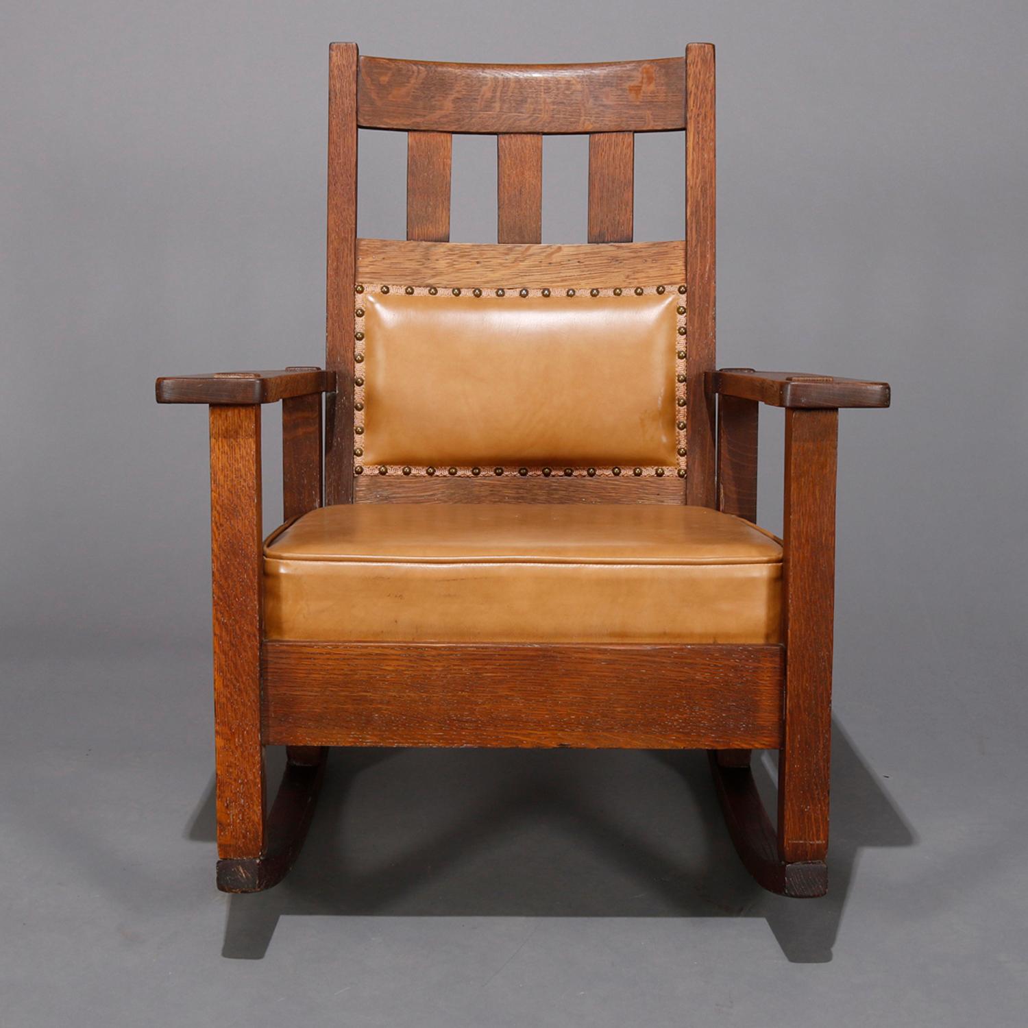 An antique Arts & Crafts Mission oak rocking chair by Stickley Bros. offers quarter sawn oak construction with slat back surmounting upholstered lumbar and seat, with even arms and slat seat, circa 1900

Measures - 34