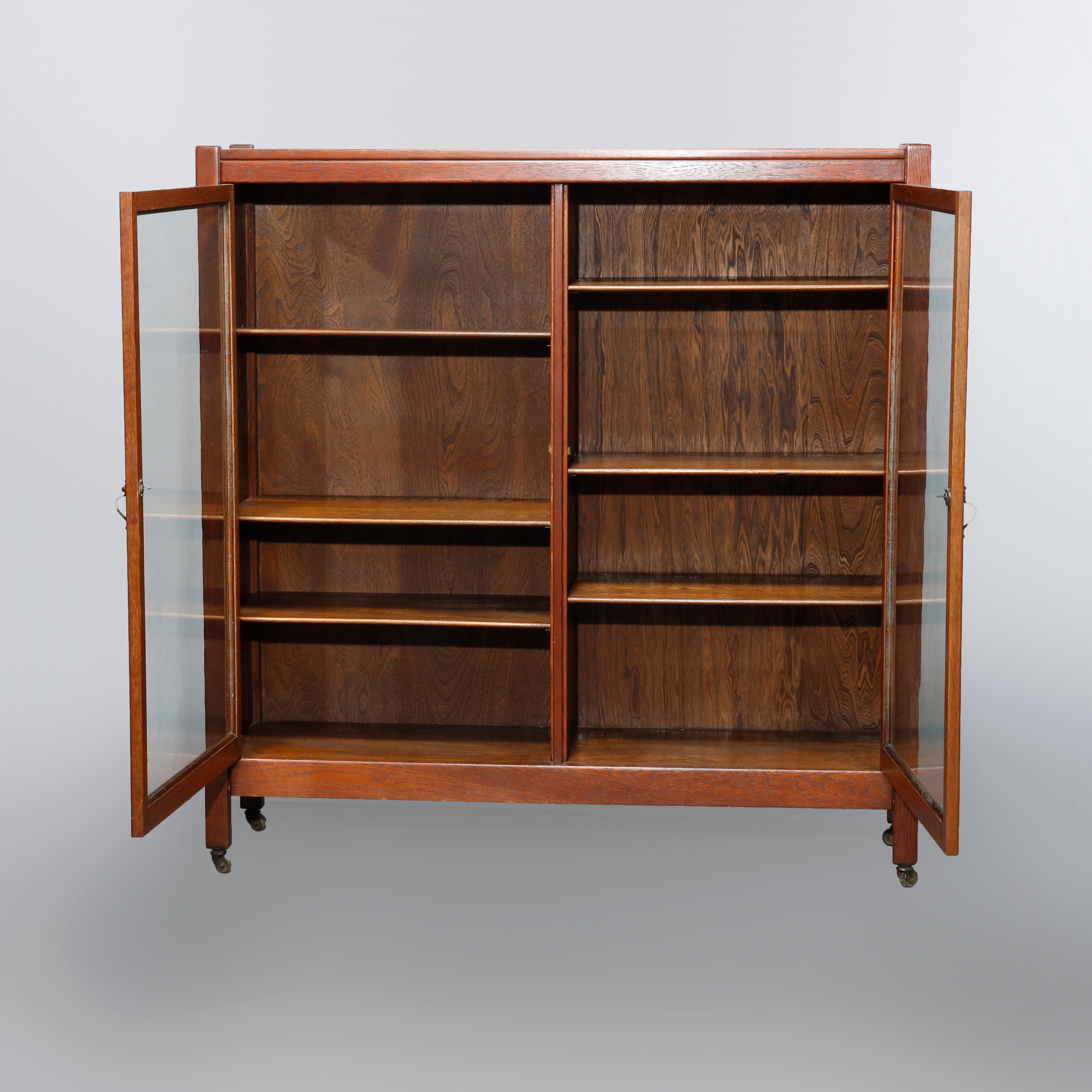 An antique Arts & Crafts Mission bookcase in the manner of Stickley offers quarter sawn oak construction with double glass doors opening to shelved interior and raised on straight and square legs, c1910

Measures: 49.75