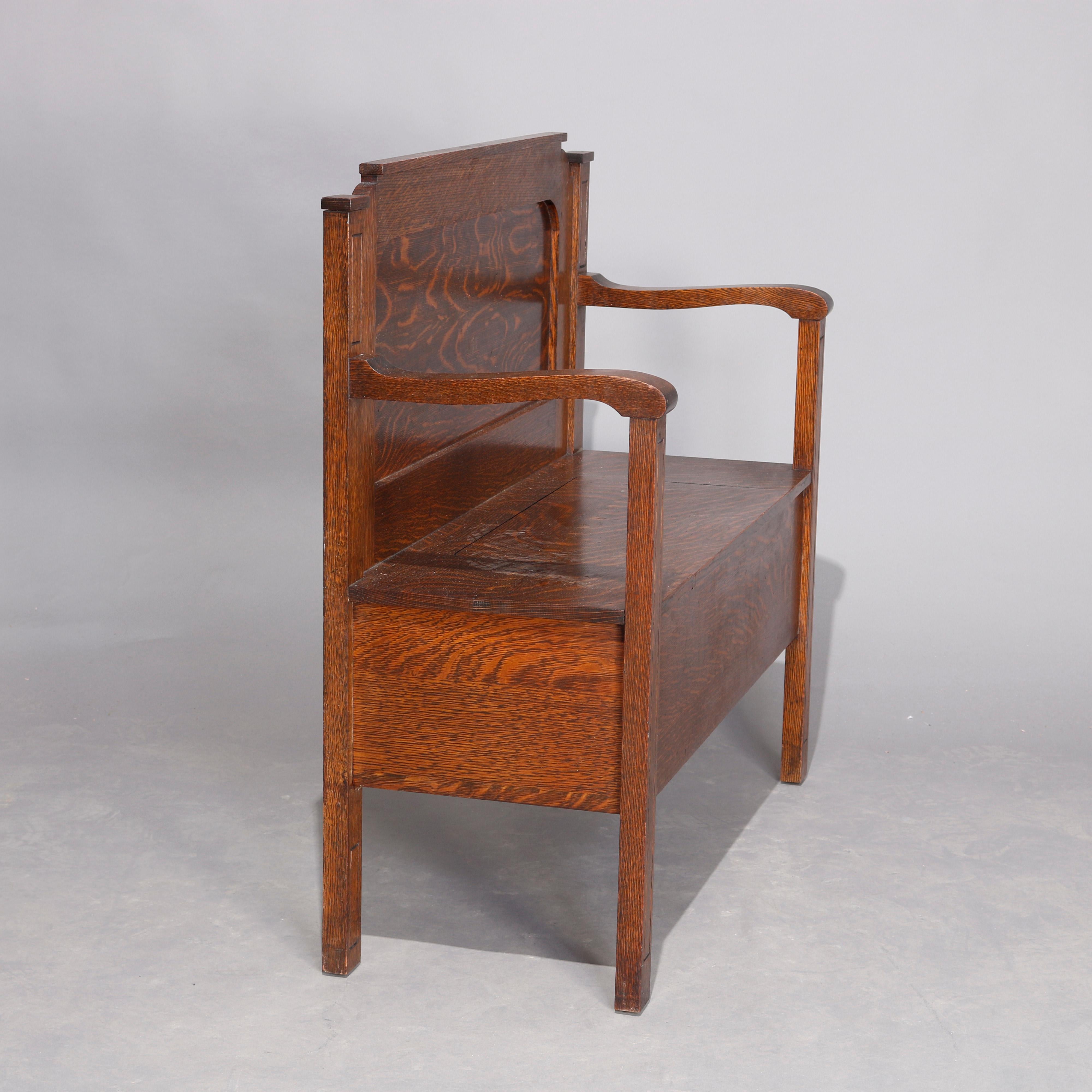 An antique Arts & Crafts mission oak Stickley School hall bench offers shaped and paneled back over lift top seat with scroll form arms, circa 1900.

Measures: 36.25