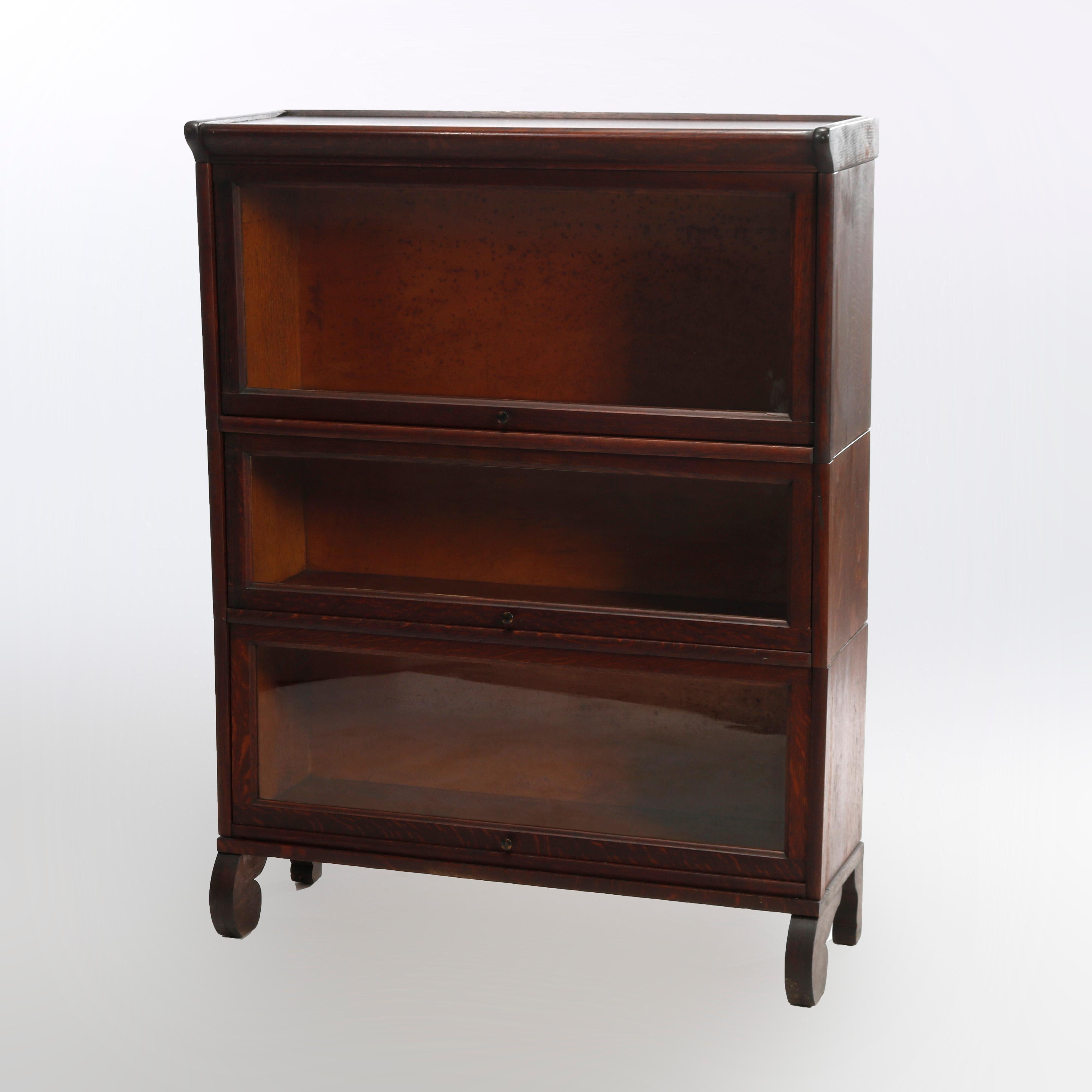 An antique Arts & Crafts Mission barrister bookcase in the manner of Globe Wernicke offers quarter sawn oak construction with three stacks, each having pull-out glass doors, and raised on scroll form legs, c1910

Measures - 45''H X 34.25''W X
