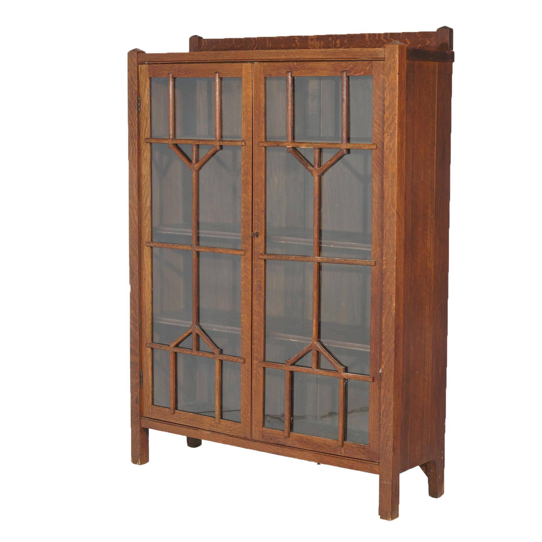 An antique Arts and Crafts Mission bookcase offers oak construction with double glass doors having cutout lattice overlay opening to shelved interior, raised on straight and square legs, c1910

Measures - 58.25
