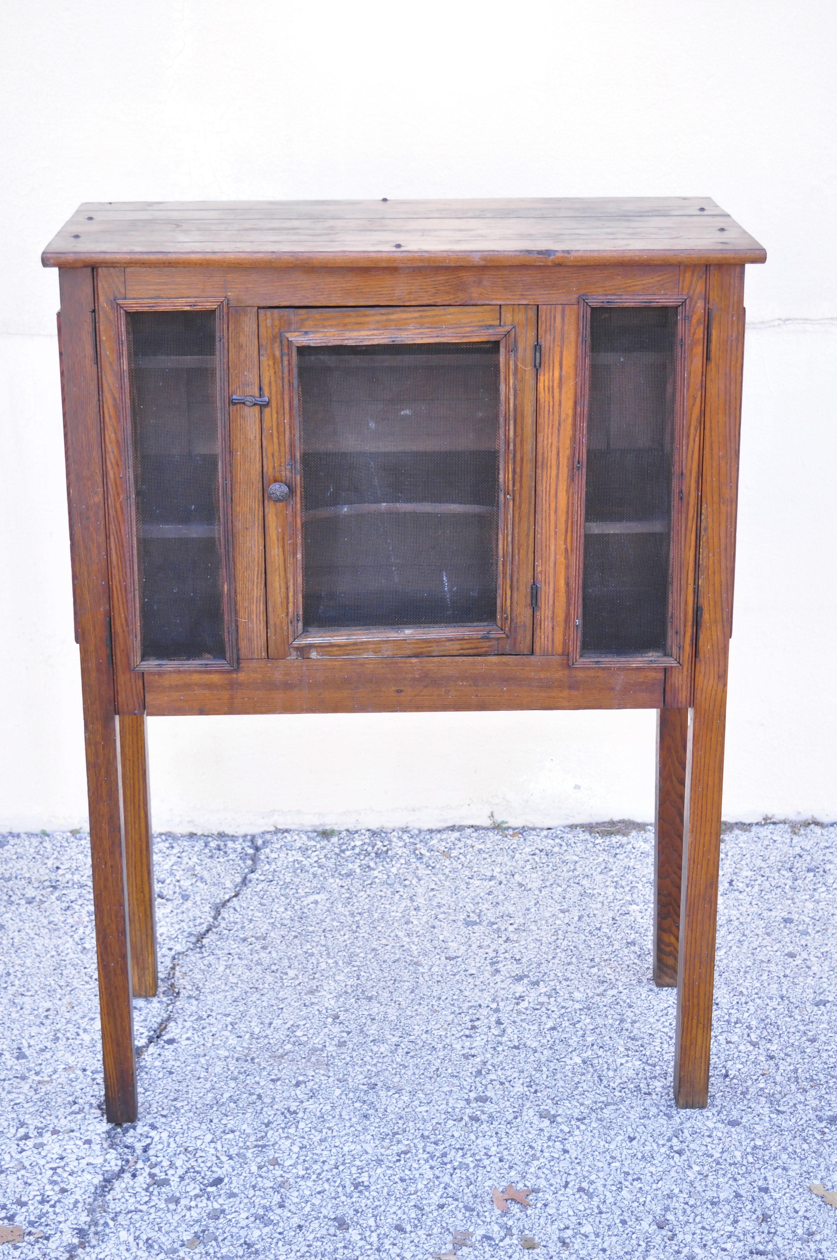 Antique Arts & Crafts Mission oak wood pie safe kitchen cupboard cabinet on legs. Item features metal mesh panels, solid wood construction, beautiful wood grain, distressed finish, 1 swing doors, wooden shelves, very nice antique item, quality