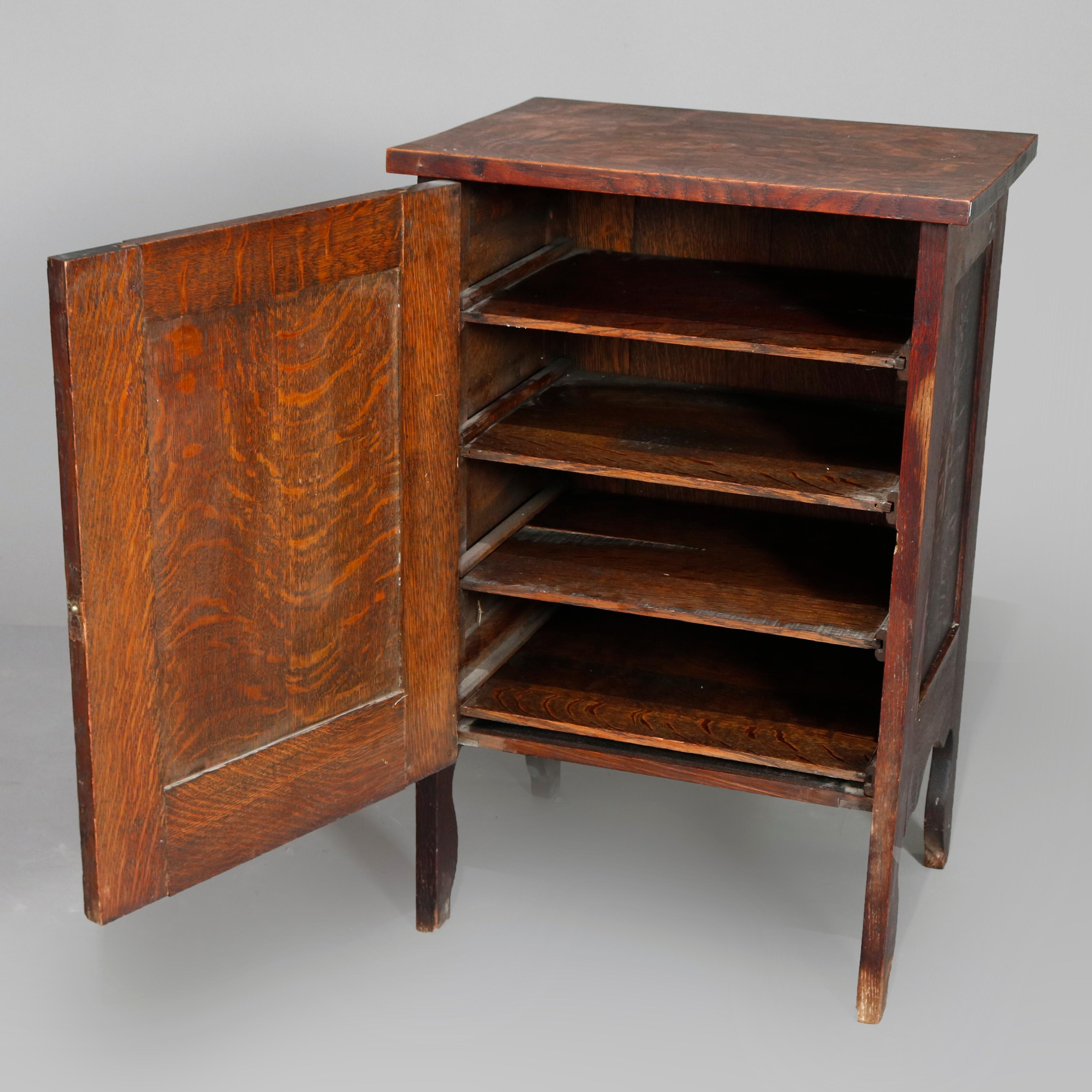 An Arts & Crafts mission oak music cabinet offers paneled quarter sawn oak construction with single door opening to shelved interior, raised on straight shaped legs, circa 1910.

Measures: 32.25