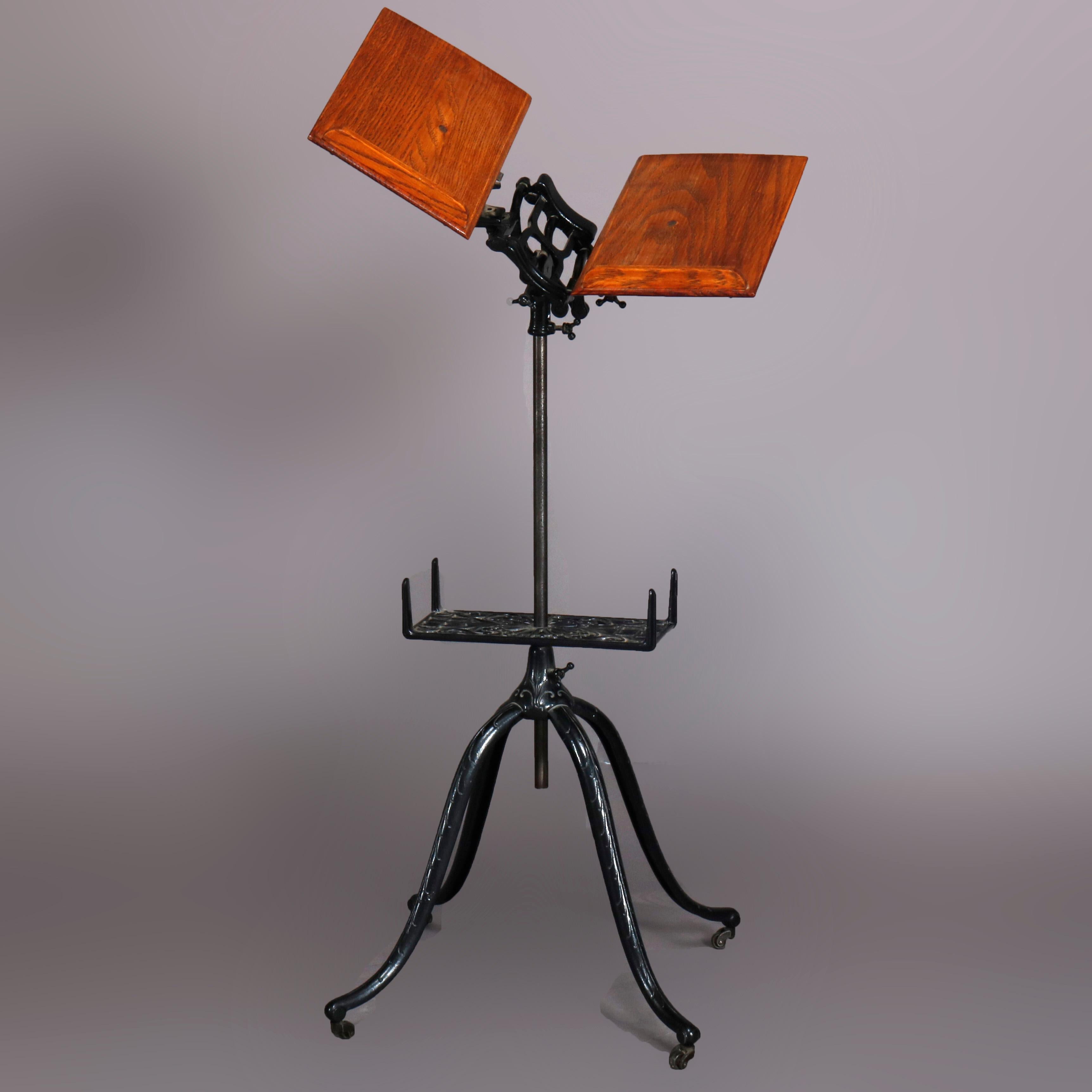 An antique Arts & Crafts library or parlor dictionary book stand offers cast iron quadrapod base with cabriole legs and pierced cast foliate lower shelf surmounted by adjustable display, seated on casters, circa 1920.

***DELIVERY NOTICE – Due to