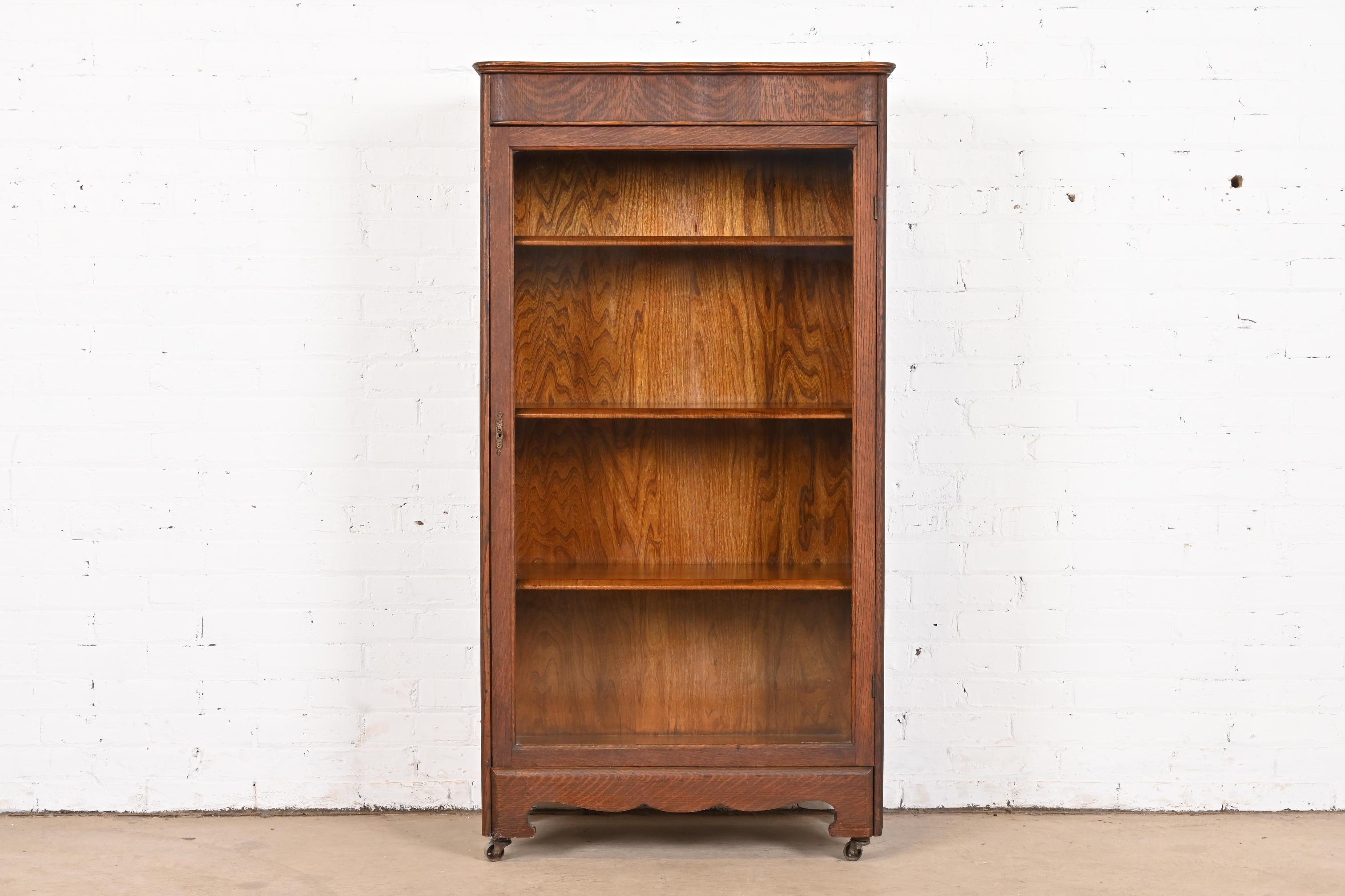 A beautiful antique Arts & Crafts or Late Victorian glass front single door bookcase cabinet

In the manner of Stickley Brothers

USA, Circa 1900

Carved quarter sawn oak, with glass front door. Cabinet locks, and key is included. Shelves are