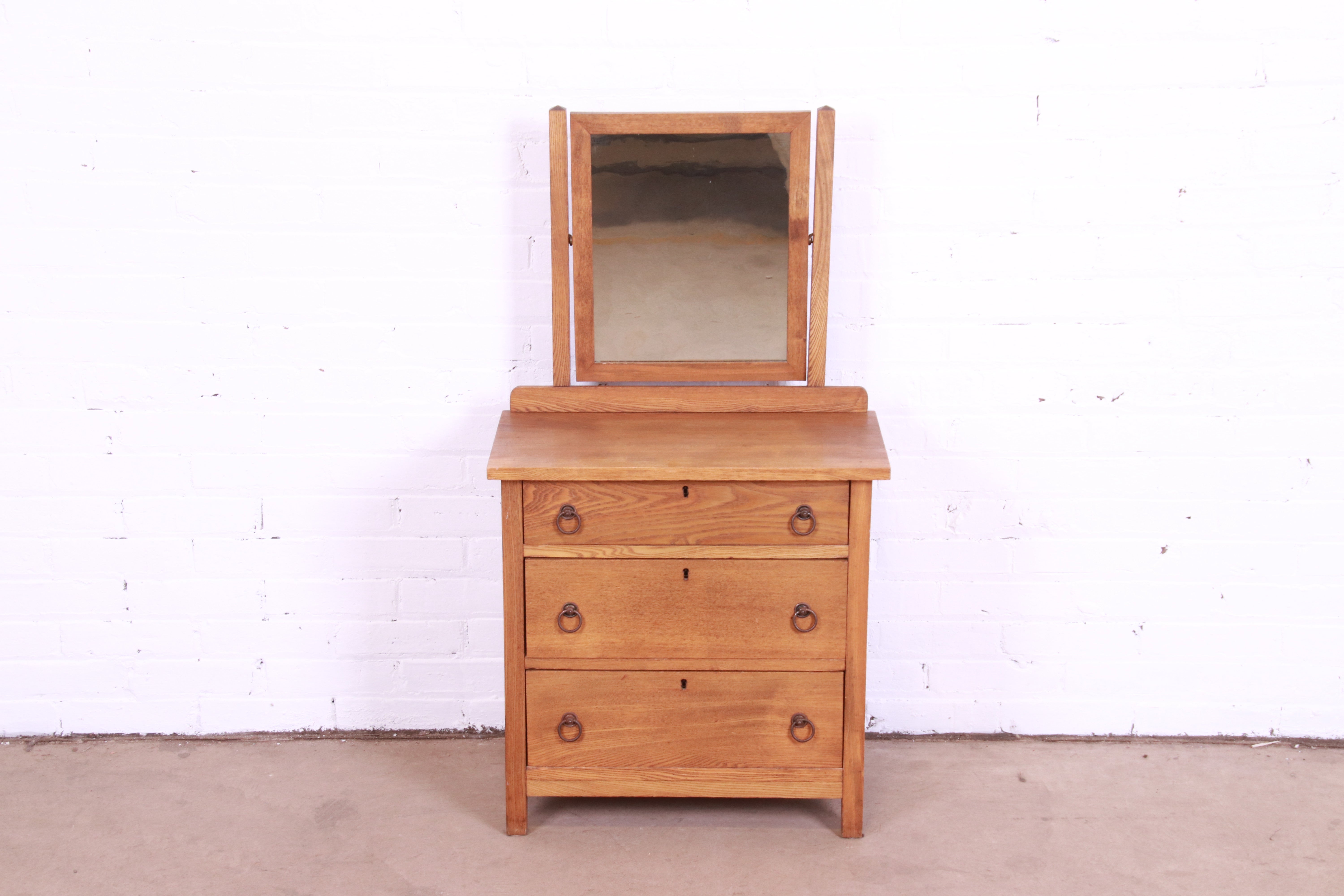 A unique antique Arts & Crafts children's oak dresser with swing mirror

In the style of Stickley

USA, Early 20th Century

Oak, with original brass hardware.

Measures: 22
