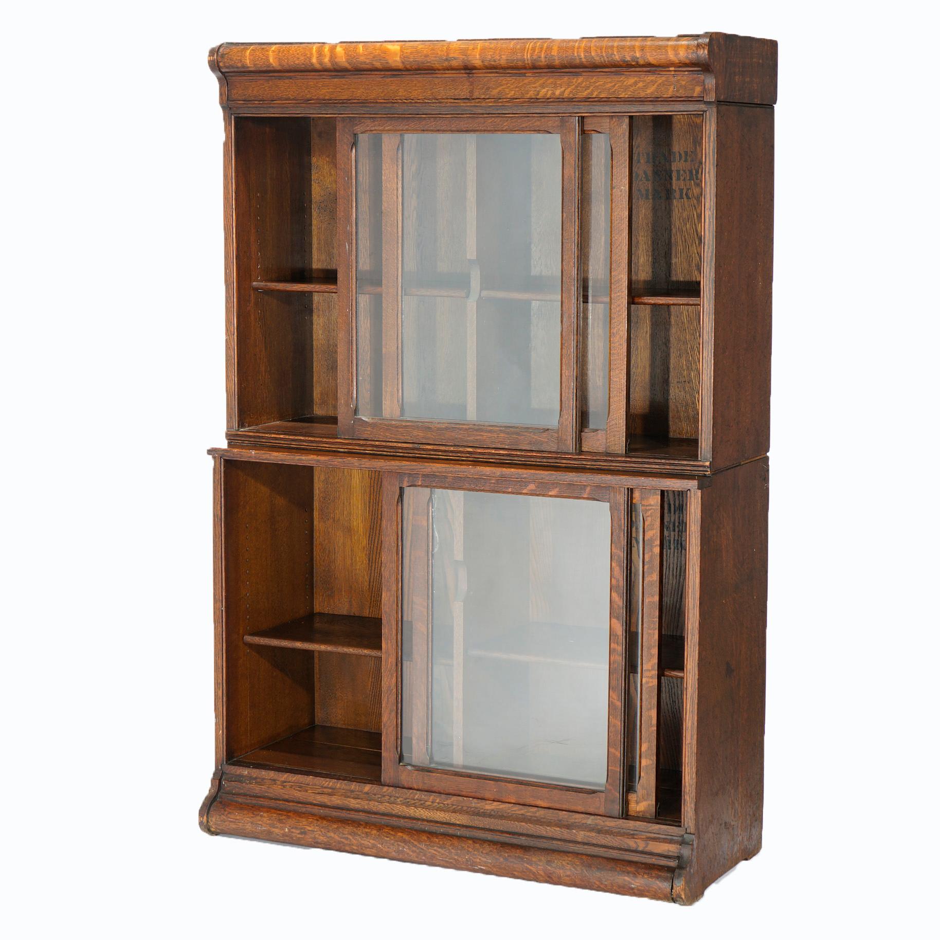 An antique Arts & Crafts bookcase by Danner offers quarter sawn oak construction with cases having sliding glass doors opening to divided and adjustable shelf interiors, raised on ogee base, c1910

Measures- 57''H x 37''W x 15.5''D.

Catalogue Note: