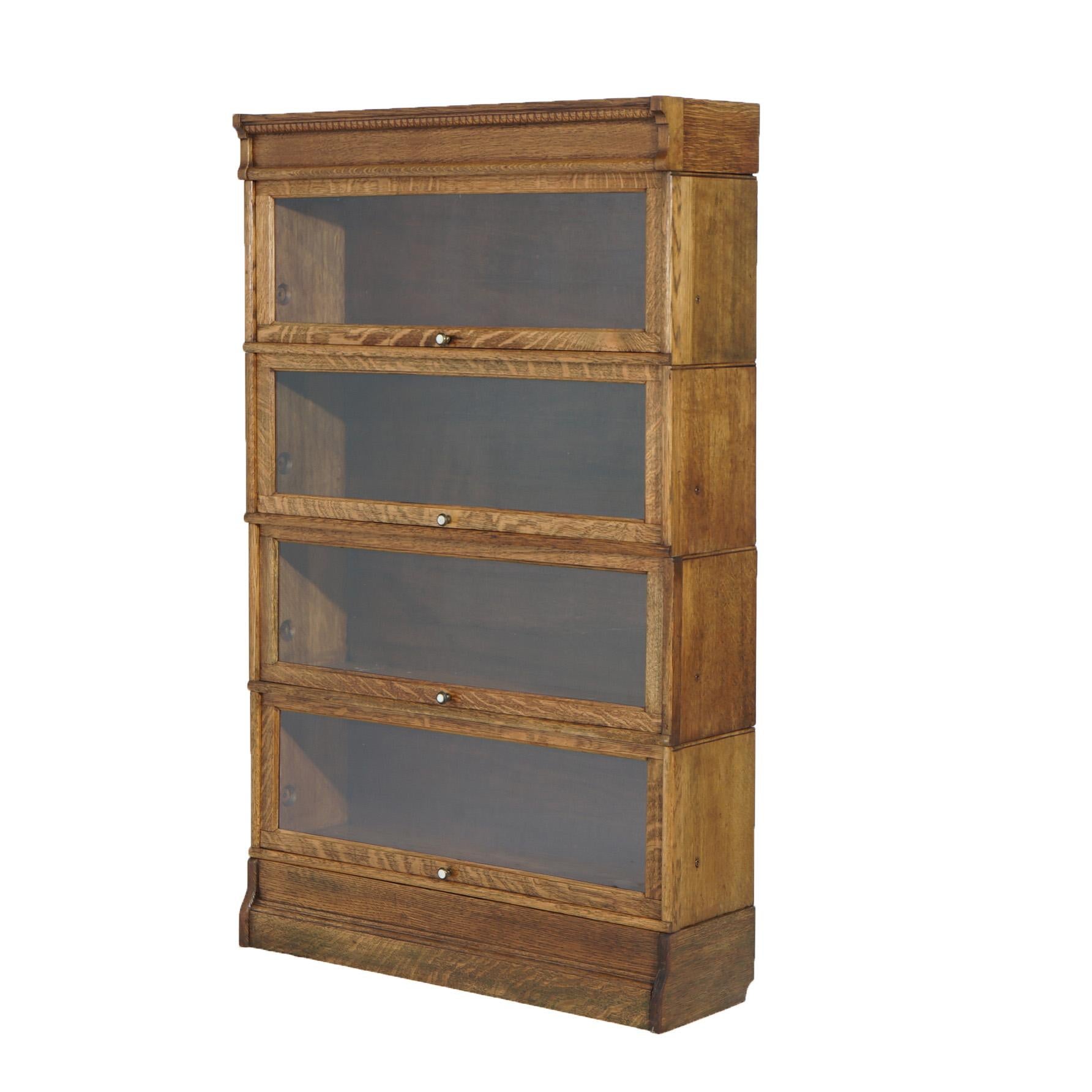 An antique Arts and Crafts barrister bookcase offers quarter sawn oak construction with incised egg and dart frieze over four stacks, each with pull out glass doors, raised on ogee base, c1910

Measures - 56.5