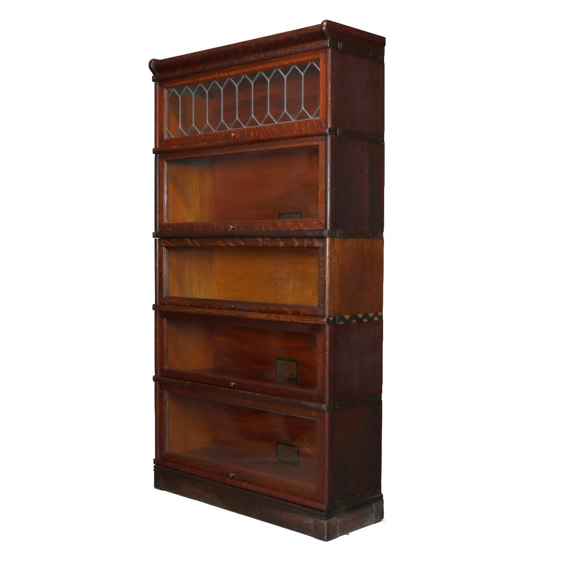 An antique Arts & Crafts Barrister bookcase by Globe Wernicke offers quarter sawn oak construction with five stacks having pull out glass doors, the top with leaded glass, original maker label as photographed, circa 1910.

Measures: 63.25