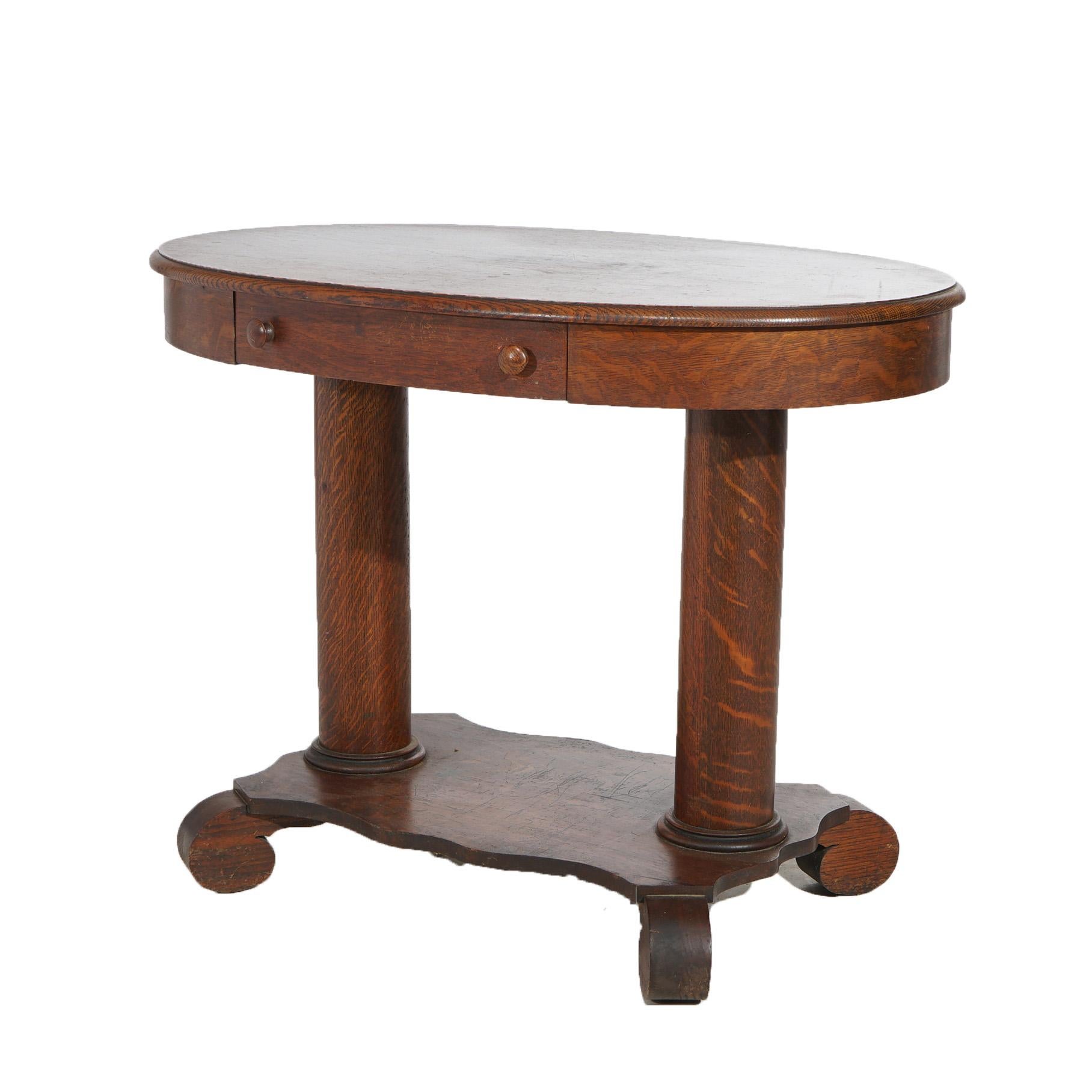 An antique Arts and Crafts library table offers quarter sawn oak construction with oval top having single drawer, raised on double pedestal base with scroll form feet, c1910

Measures - 29.25