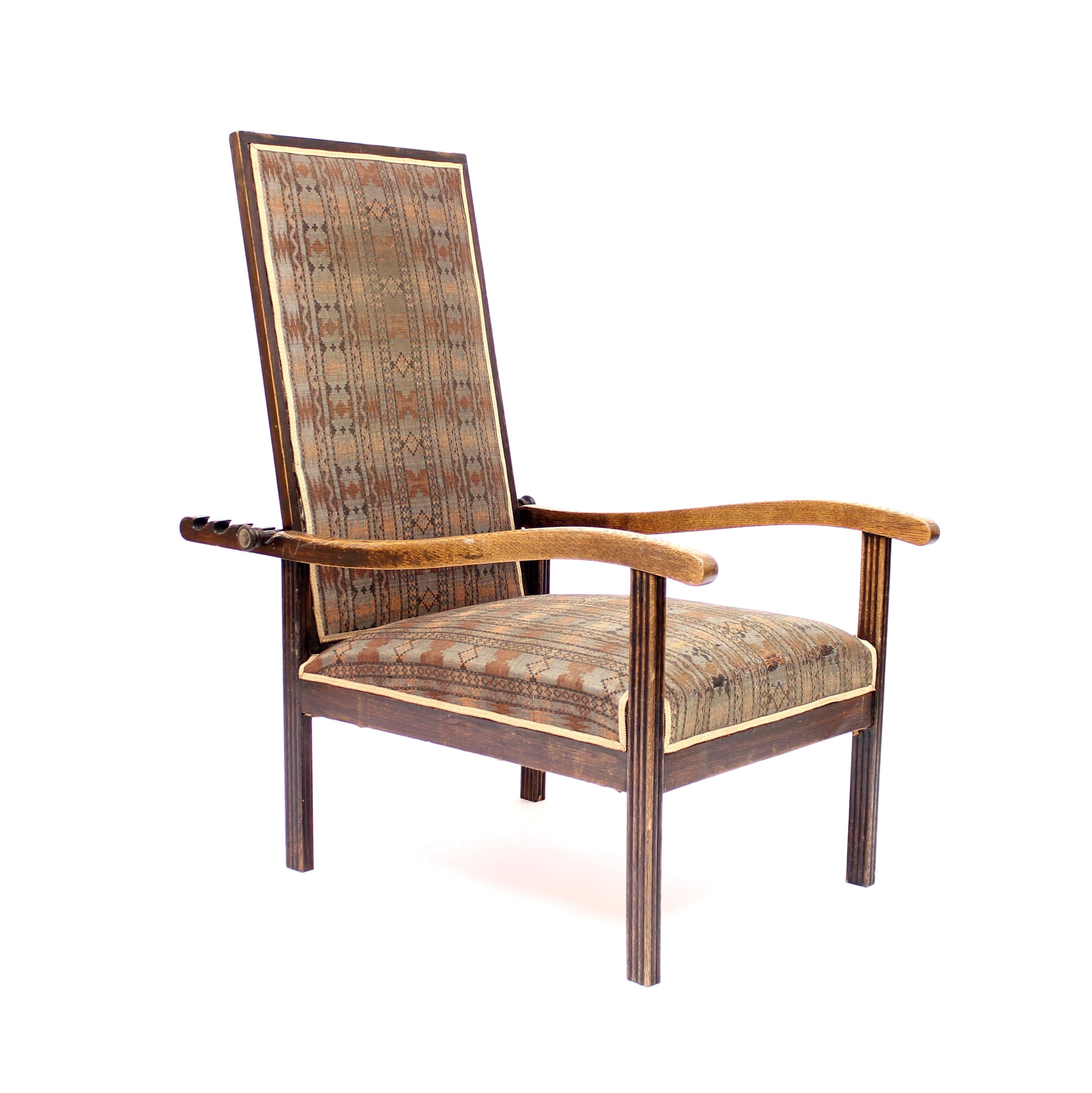 Deep seated Arts & Crafts recliner in oak, possibly English and possibly retailed by Heal's of London, from the early 20th century. Seat and back covered in what is most likely the original fabric. The back can be adjusted in 4 different positions