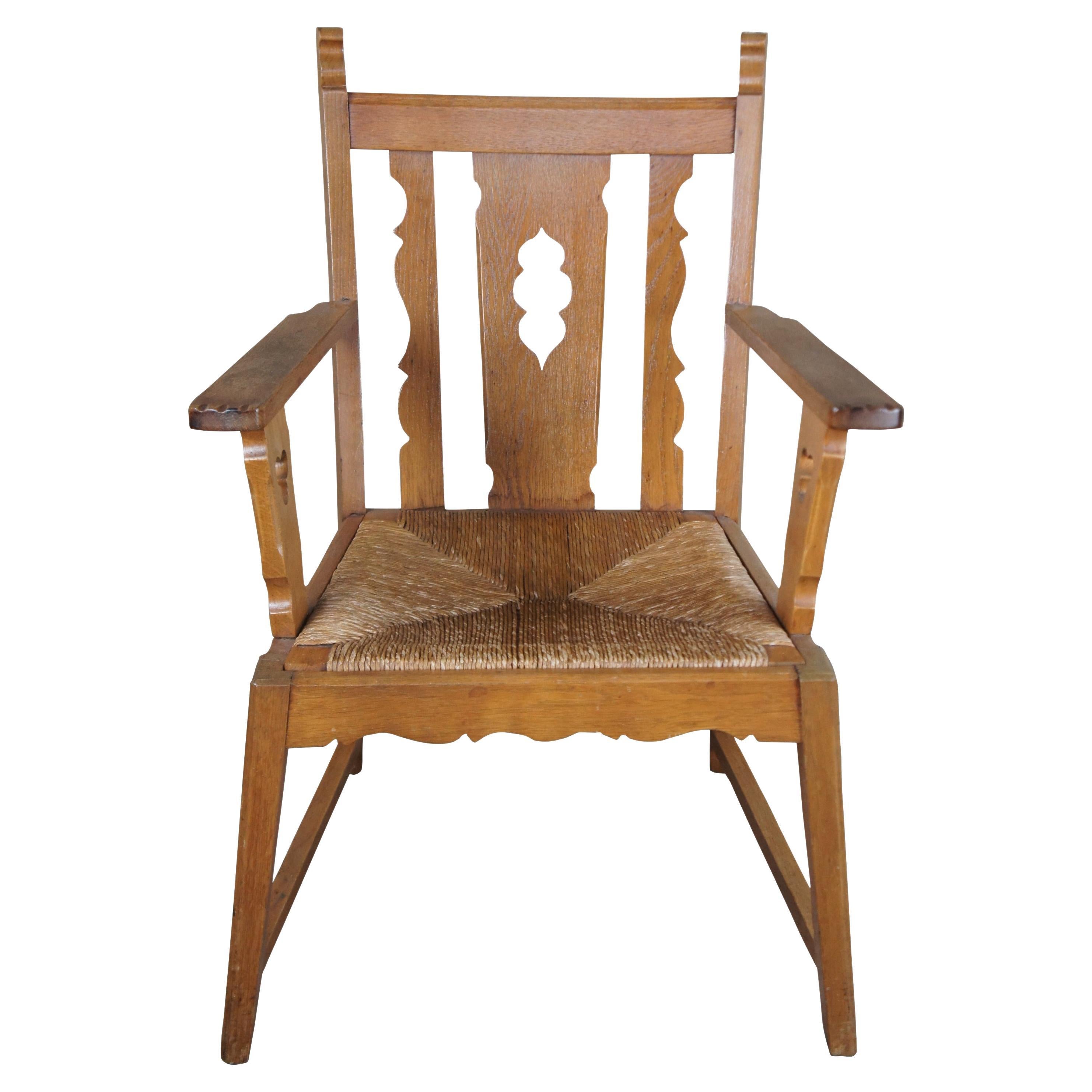 Antique arts & crafts library armchair. Made of oak featuring a rush seat with pierced clover and serpentine design. Old World Carvings and shaping give off the feel of an Irish design. Includes slip seat cushion.

23