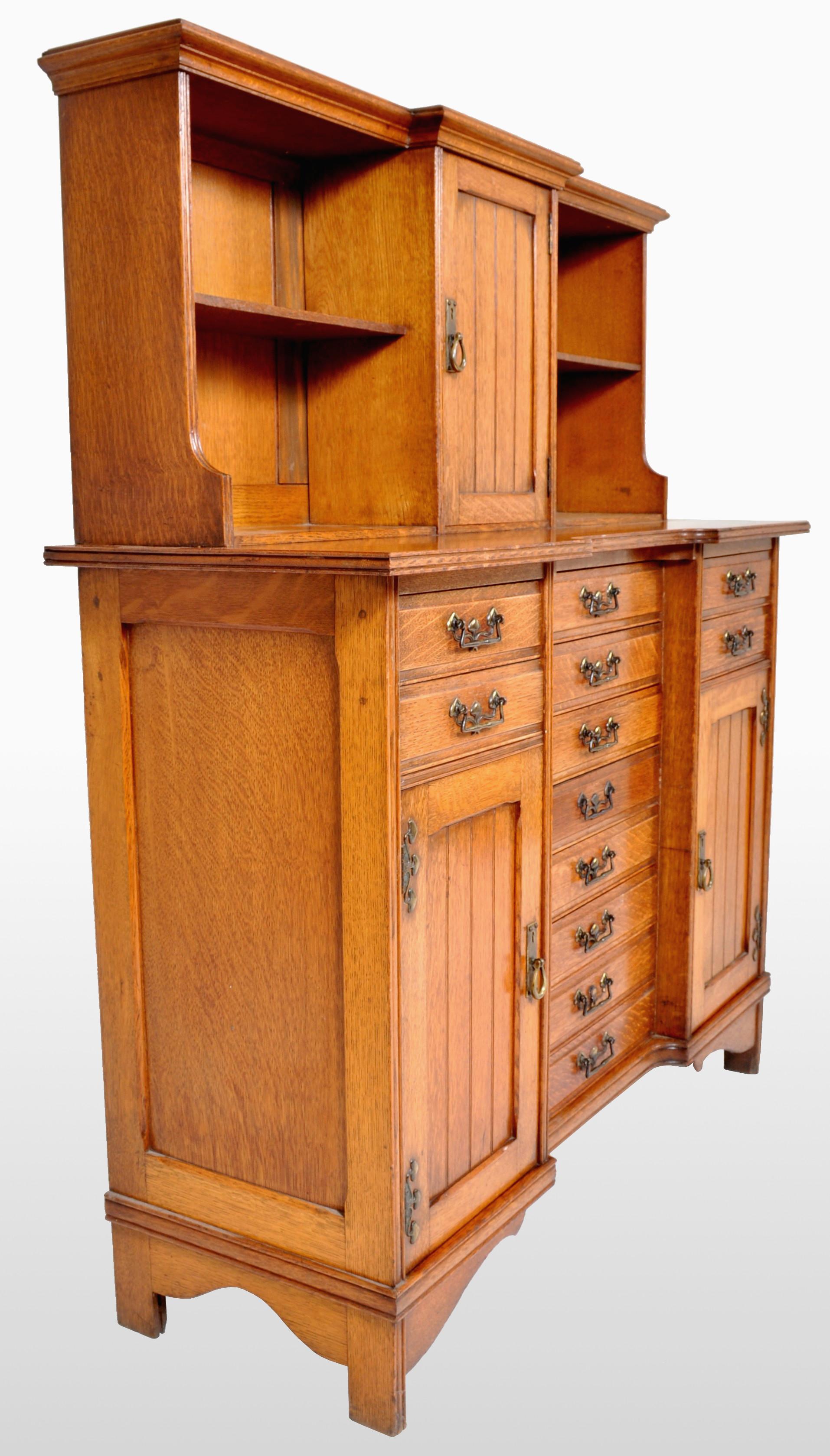 Antique Arts & Crafts oak sheet music cabinet, circa 1890. The back having two bookcases with a central cupboard enclosing one shelf. The base of reverse break-front form, having a central bank of eight drawers, flanked by two cupboard doors with