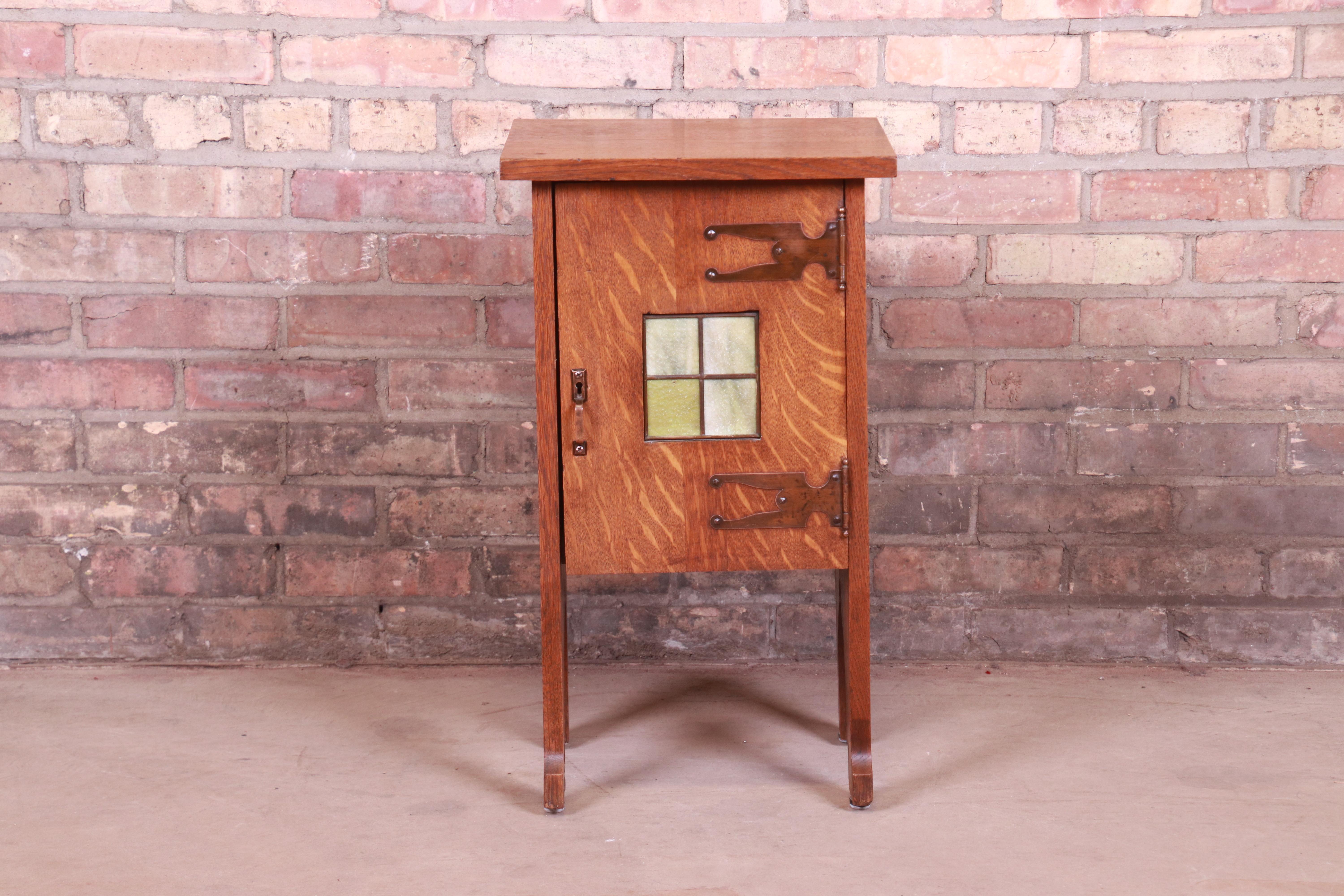 A gorgeous antique Arts & Crafts occasional side table cabinet

In the manner of Stickley

USA, circa 1900

Quartersawn oak, with original copper hardware and unique stained glass tile insert.

Measures: 14