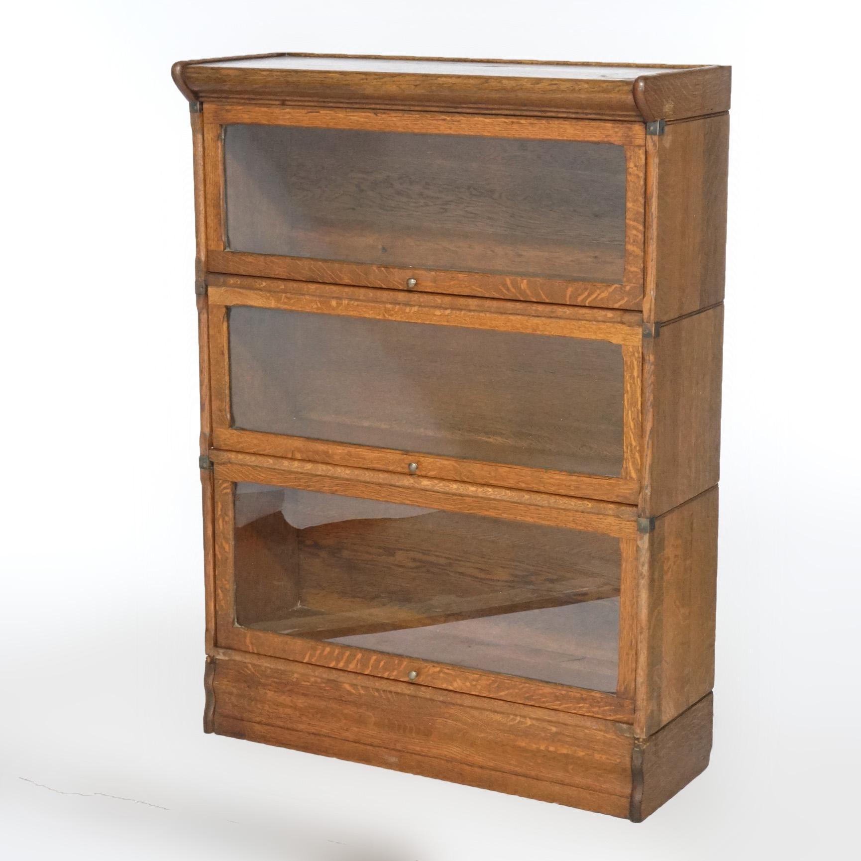 An antique Arts & Crafts barrister bookcase in the manner of Globe Wernicke offers quarter sawn oak construction with three stack having pull out glass doors, raised on ogee base, circa 1910.

Measures- 47.25''H x 34''W x 13.5''D.