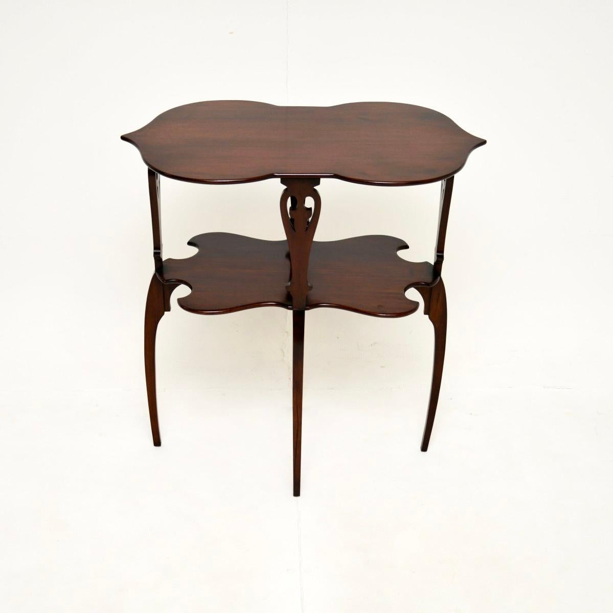 Maravillosa mesa auxiliar antigua. Fabricada en Inglaterra, data aproximadamente del periodo 1890-1910, con un elemento de diseño Arts and Crafts.

Es de muy buena calidad, la parte superior tiene una hermosa forma con bordes serpenteantes. Las