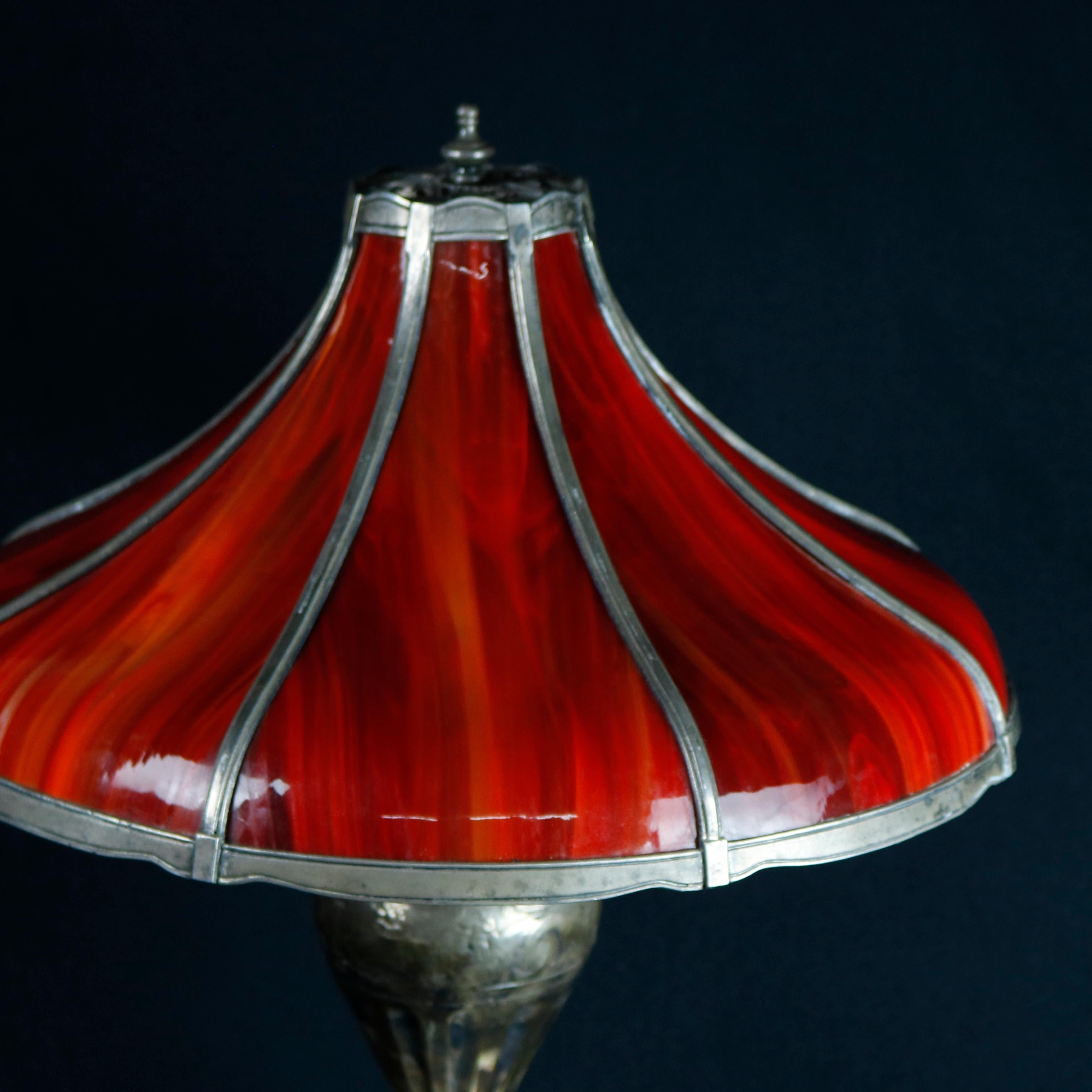 An antique Arts & Crafts pairpoint table lamp offers paneled bent reg slag glass shade surmounting embossed urn form base having three independently controlled light sockets, signed on base as photographed, circa 1920

Measures: 23.5