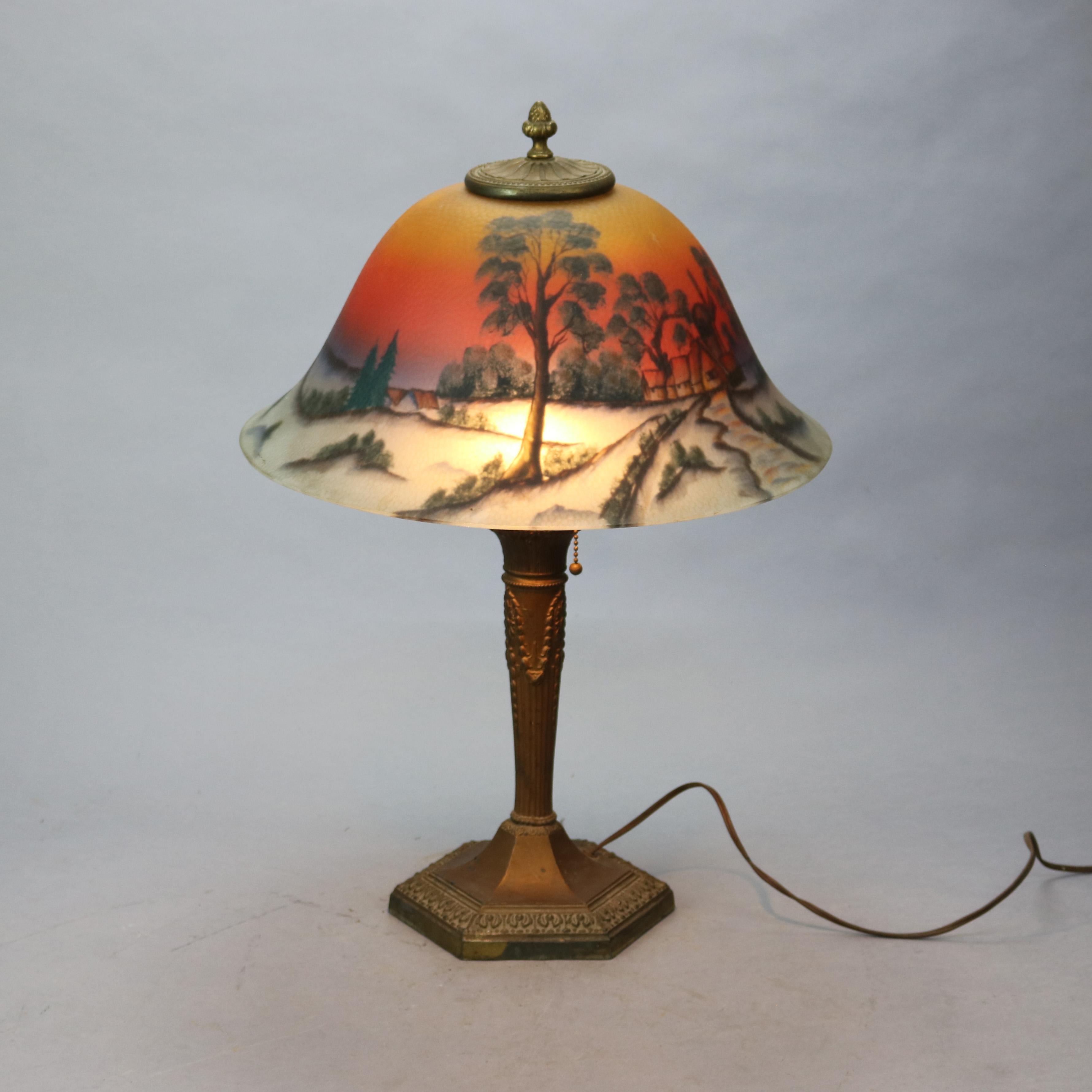 An antique Arts and Crafts lamp by Phoenix offers bell form shade with reverse painted landscape scene over cast double socket metal base, c1920

Measures - 23.5''H x 16.25''W x 16.25''D.