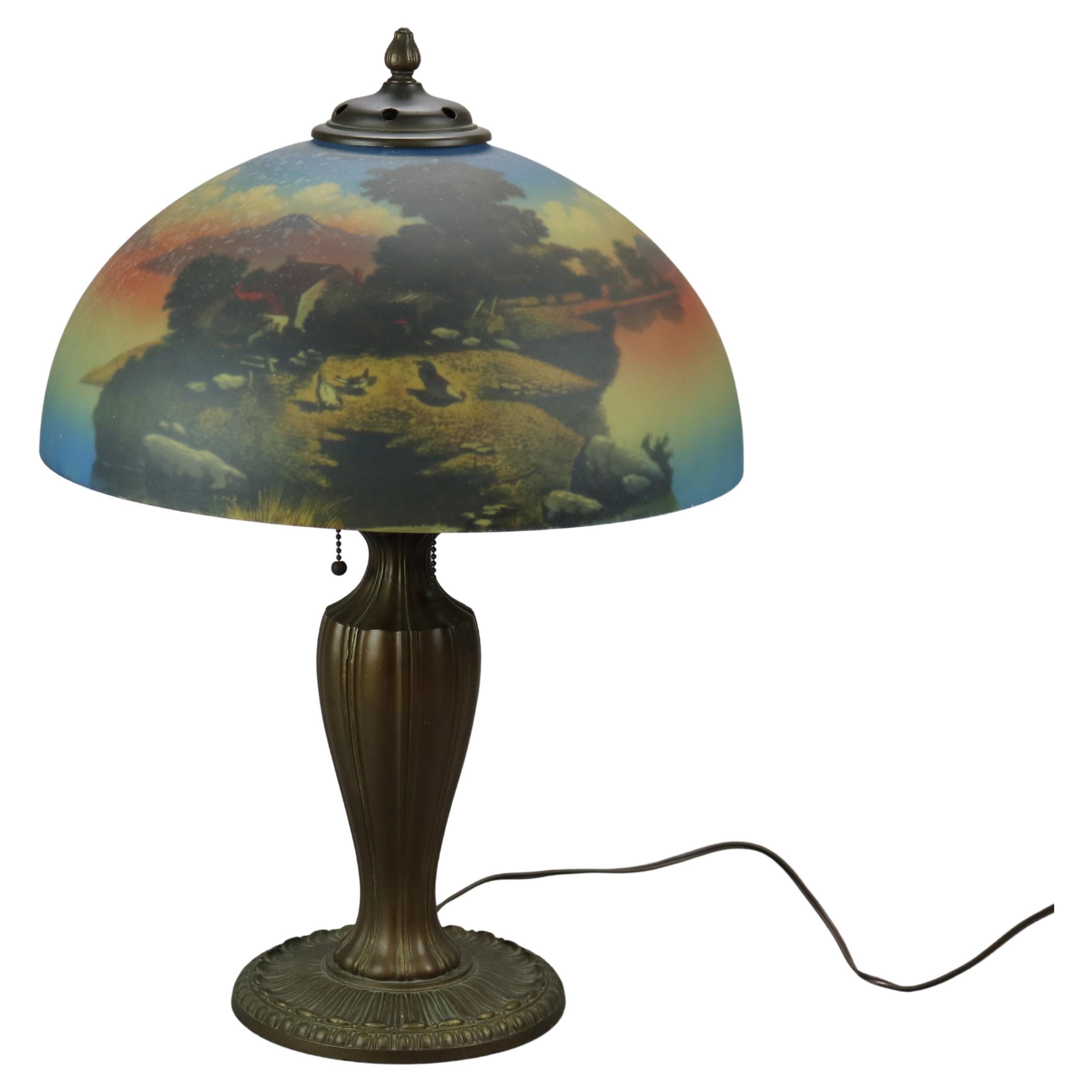 An antique Arts & Crafts table lamp attributed to Phoenix offers reverse painted glass dome shade with farm scene including farmhouse and chickens over double socket cast base, c1920

Measures - 23''h x 16''w x 16''d.