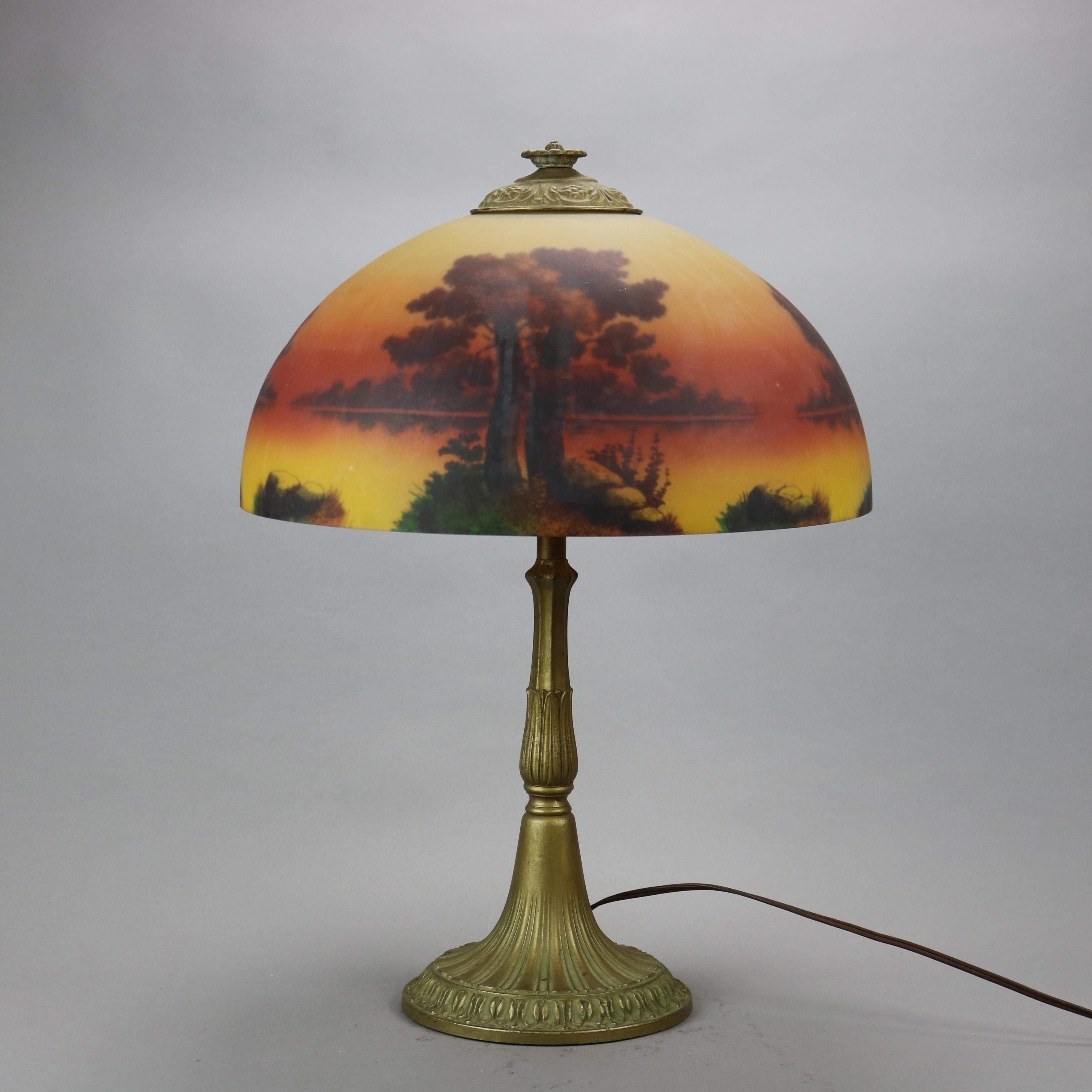 An antique Arts & Crafts table lamp attributed to Phoenix offers reverse painted glass dome shade with landscape scene over double socket cast base, c1920

Measures - 22.25''H X 16''W X 16''D.